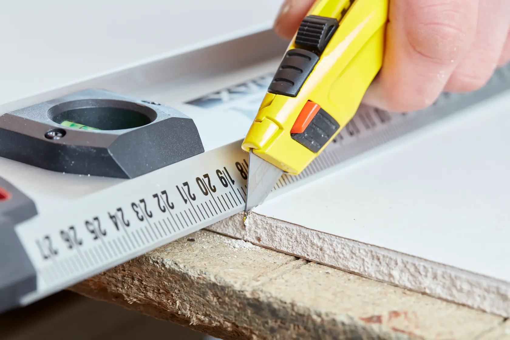 STANLEY 0-10-778 utility knife used to cut drywall along a metal ruler, close-up angle.