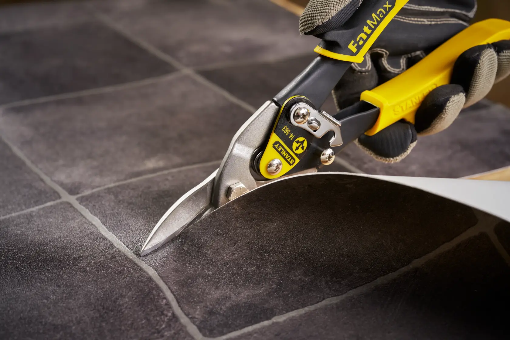 STANLEY 2-14-563 aviation snips with yellow handle cutting tile sheet close-up.