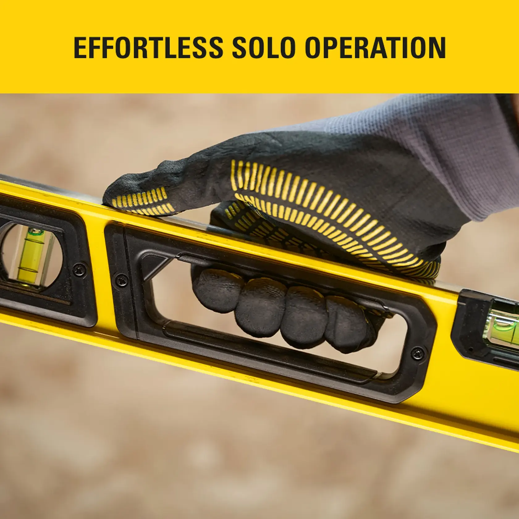 Photo of STANLEY STHT41036-0 spirit level with glove hand gripping ergonomic handle, close-up view.