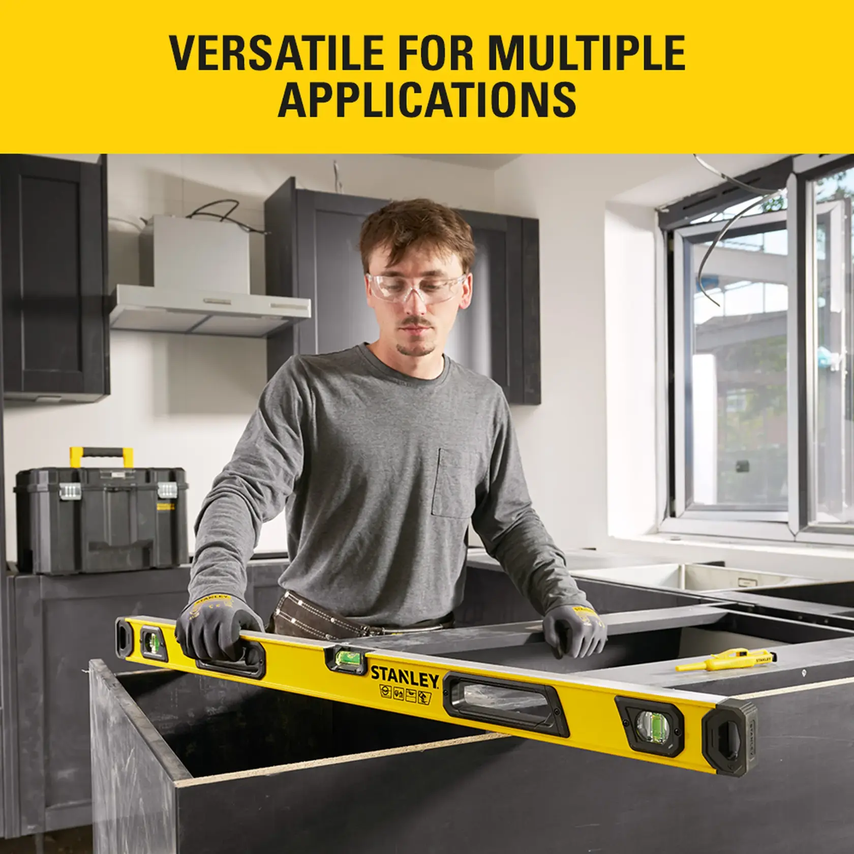Photo of STANLEY STHT41036-0 spirit level in use during cabinet installation, worker measuring with tool indoors.