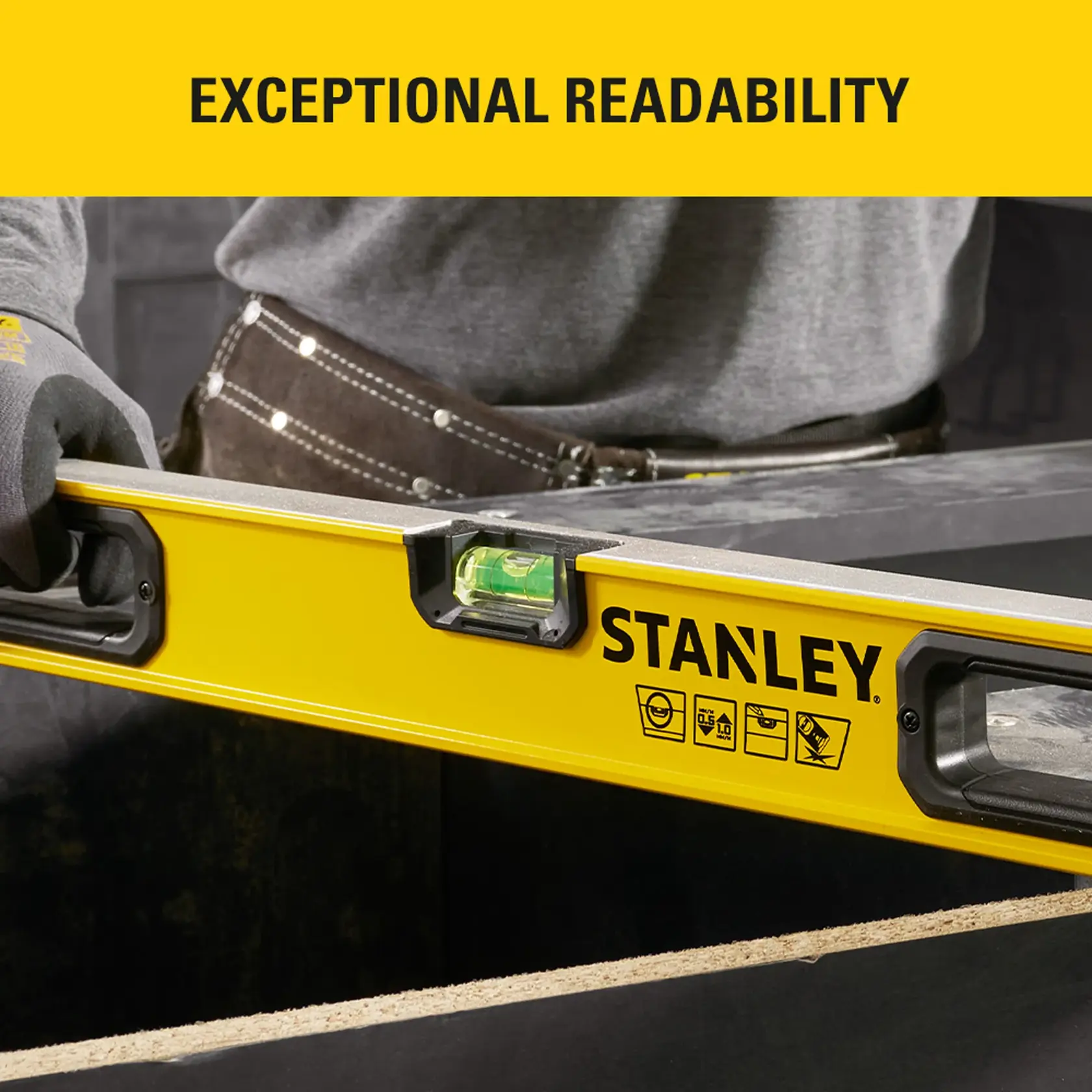 Photo of STANLEY spirit level STHT41036-0 with bright yellow body, ergonomic handles, and clear vial in use.
