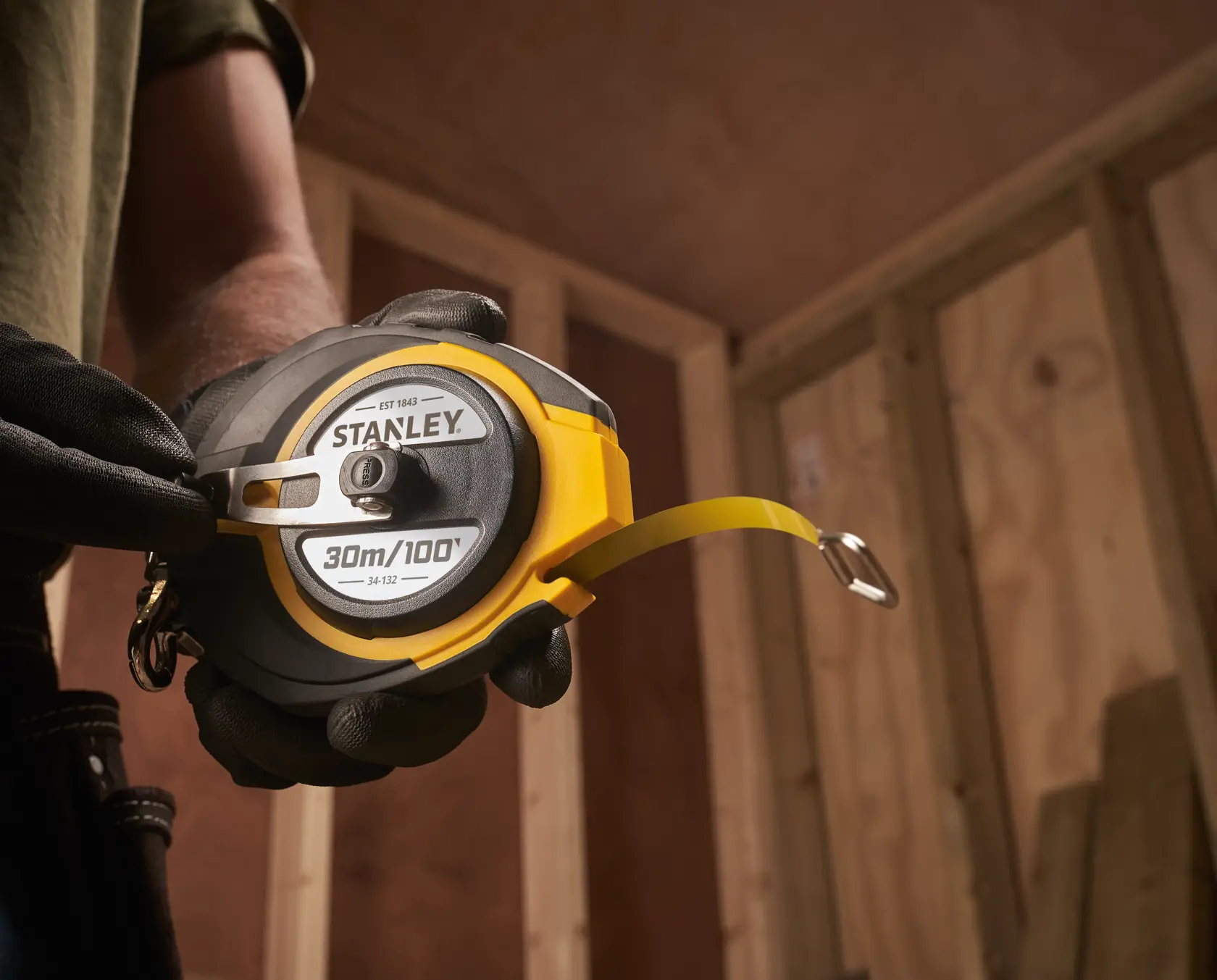 Photo of STANLEY 0-34-132 FatMax 30m/100ft tape measure held by a person wearing gloves.