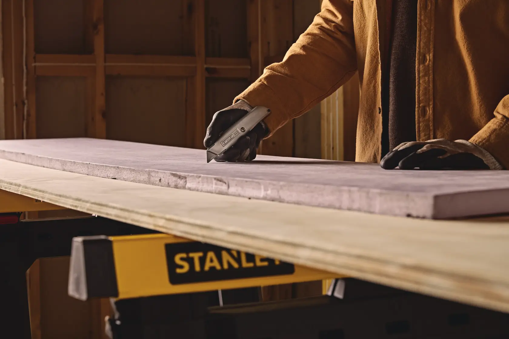 Stanley 10-099 utility knife cutting foam board on workbench in workshop, close-up photo.