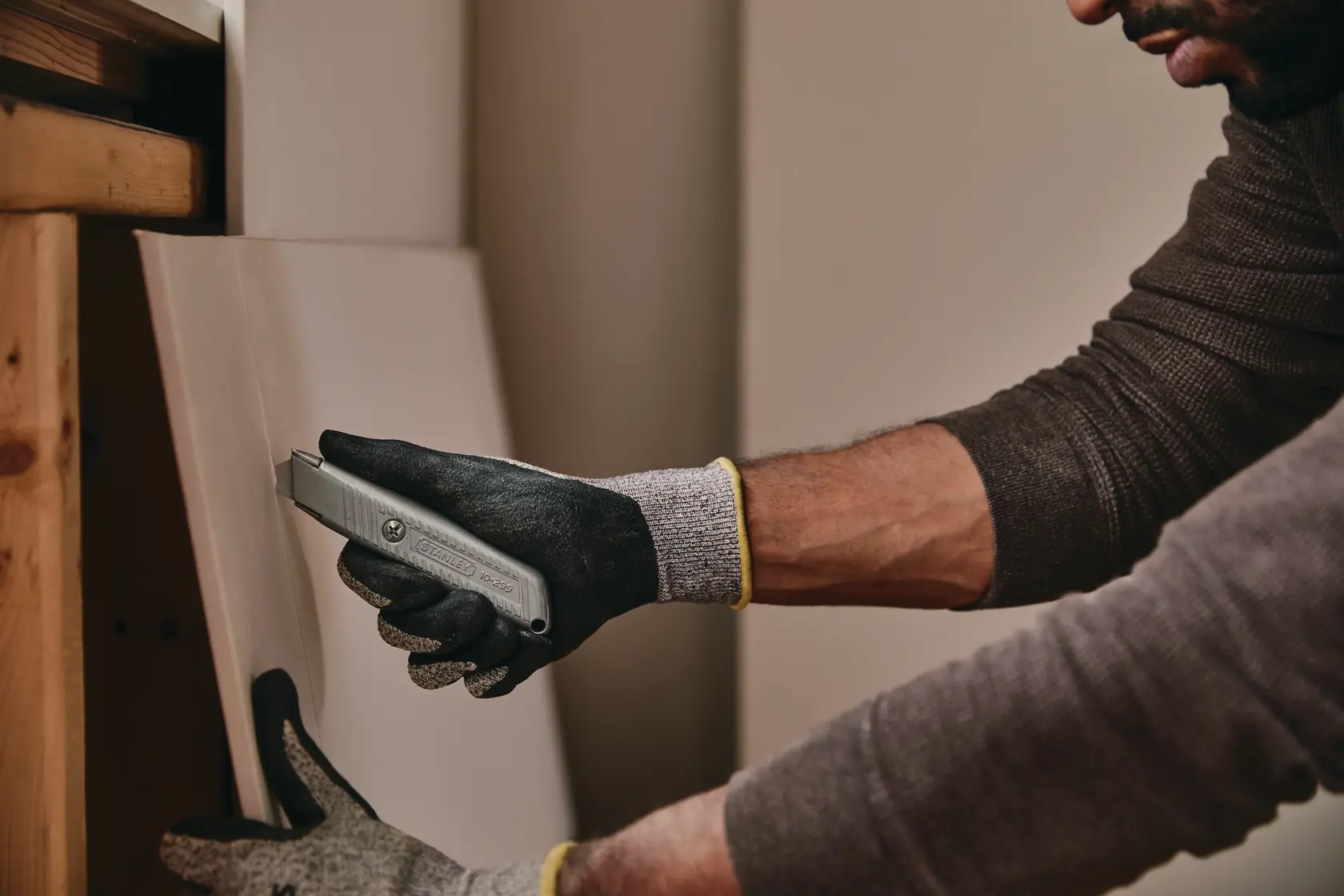 STANLEY 10-299 utility knife in use cutting board, worker wearing safety gloves.