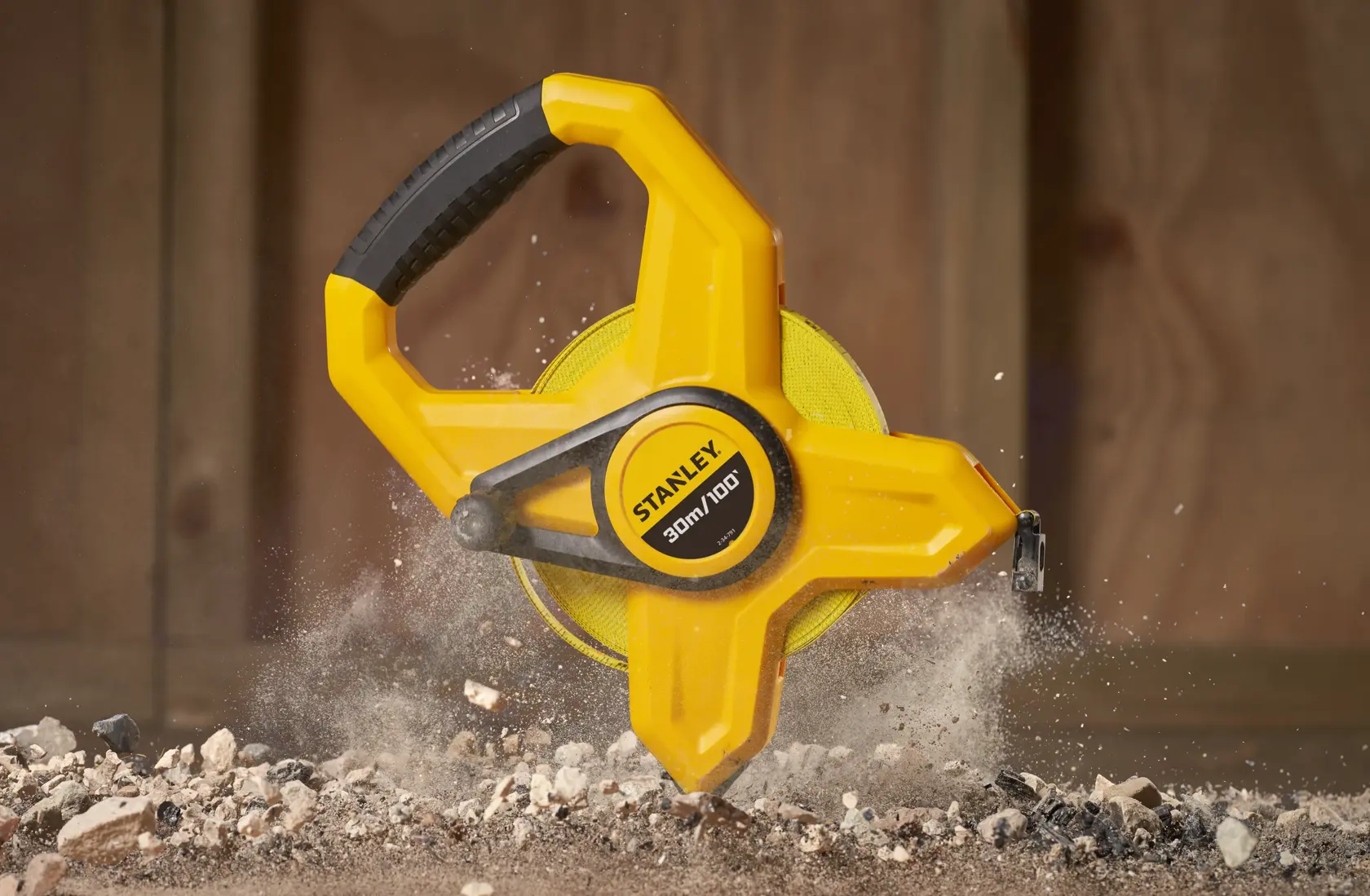 Photo of STANLEY 34-791 open reel yellow tape measure on construction debris, close-up side view.
