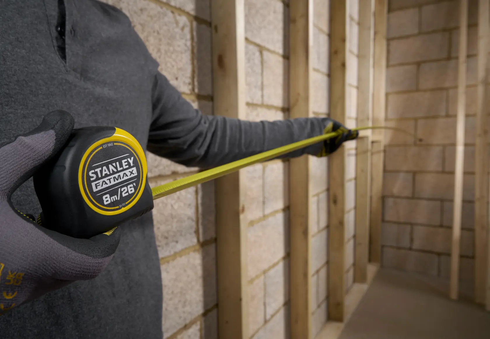 Photo of STANLEY 33-731 tape measure extended, used for wall measuring, person wearing gloves.