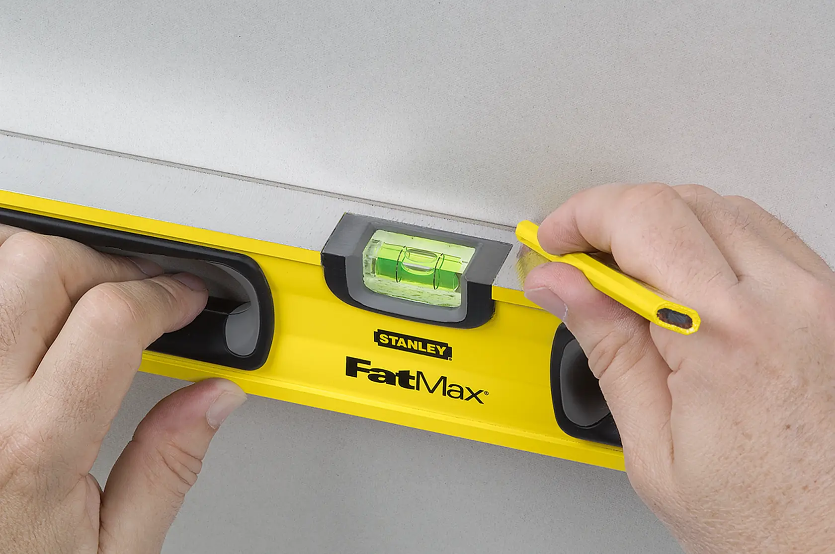Stanley 43-524 FatMax level tool photography showing hands using pencil on wall.