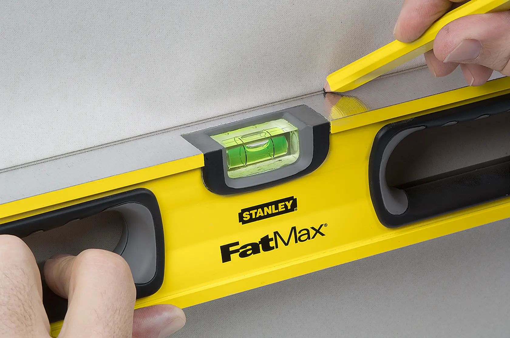 STANLEY 43-524 FatMax level being held and marked with pencil, closeup of yellow tool in use.