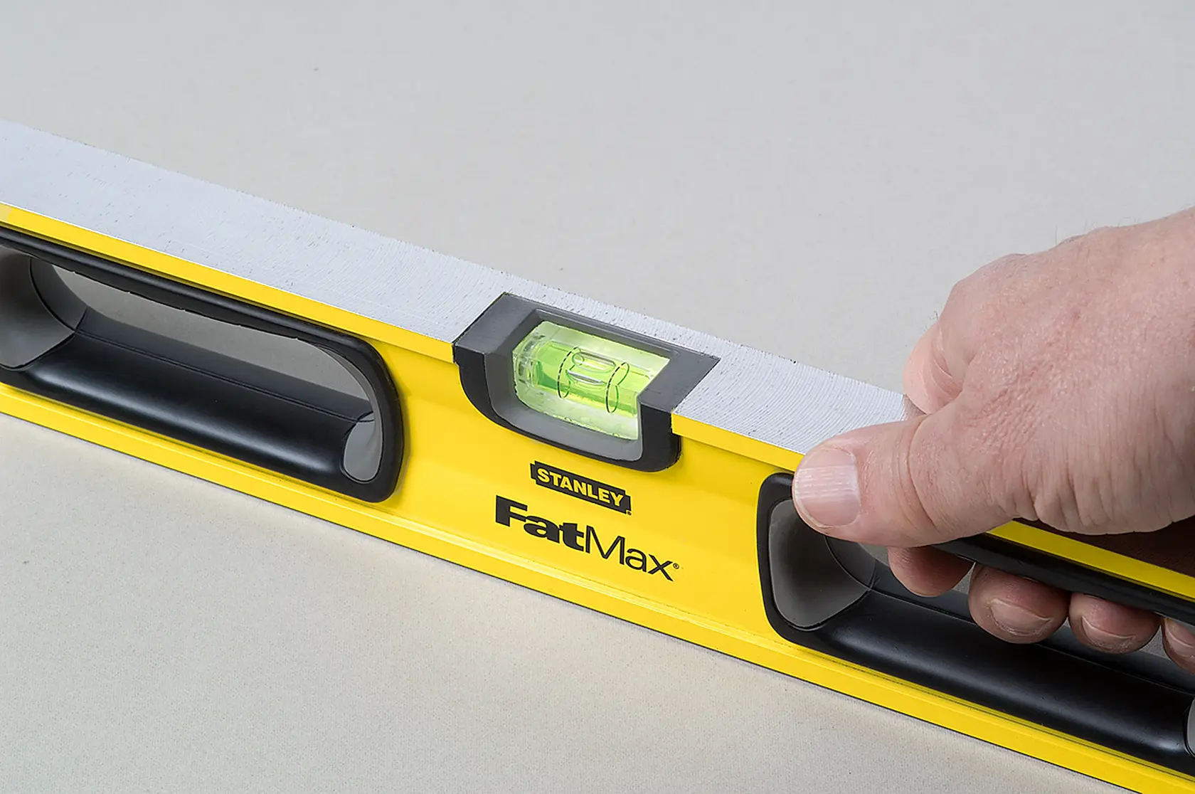 Photo of STANLEY 43-524 FatMax spirit level held in hand, yellow body with black handles and visible vial.