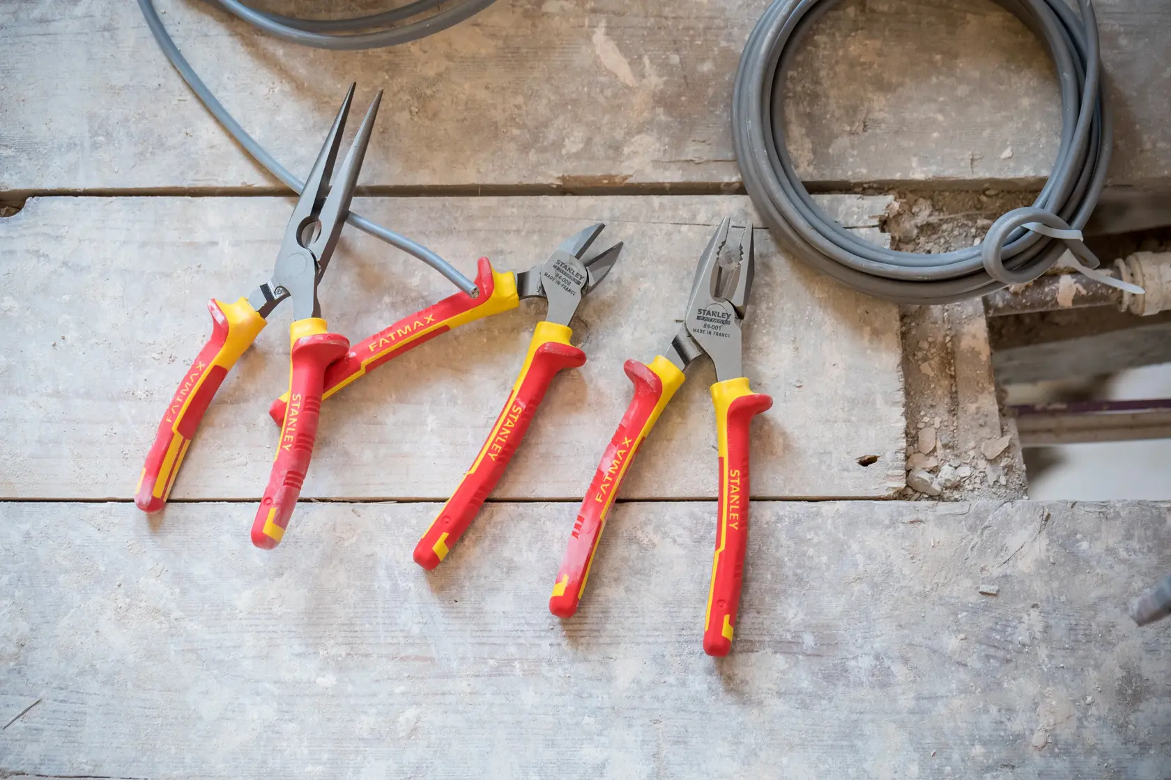 STANLEY 84-011-S insulated pliers set with red and yellow handles on wooden surface, three types for electrical work.