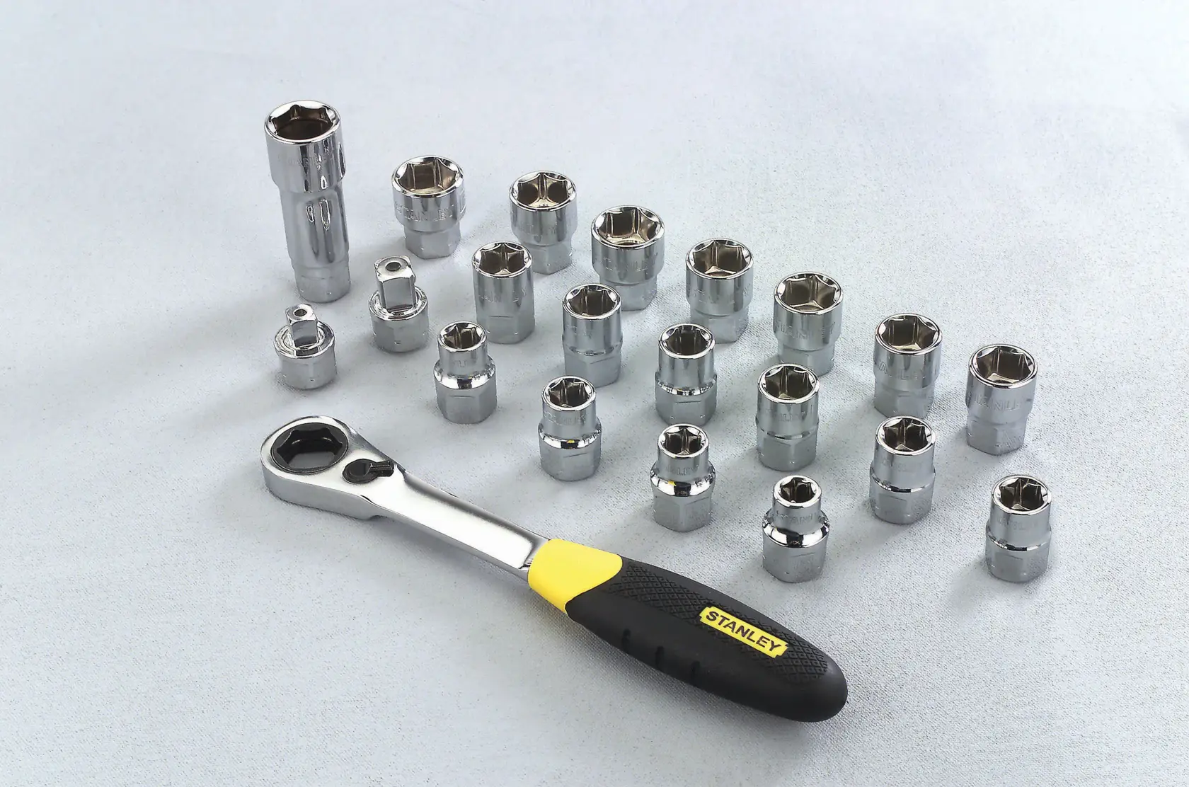 Stanley ratchet wrench with multiple chrome sockets arranged on a light surface.