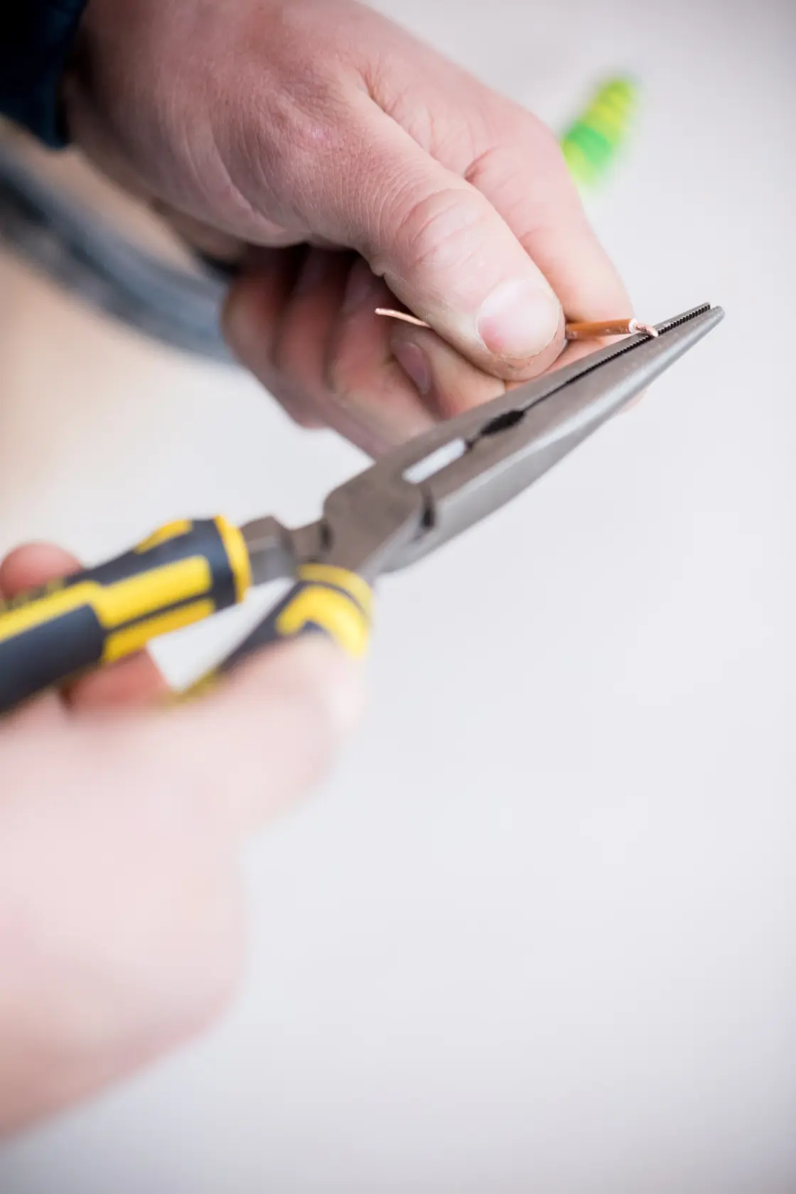 Photo of STANLEY 89-870 long nose pliers with yellow and black handle in use gripping a wire.