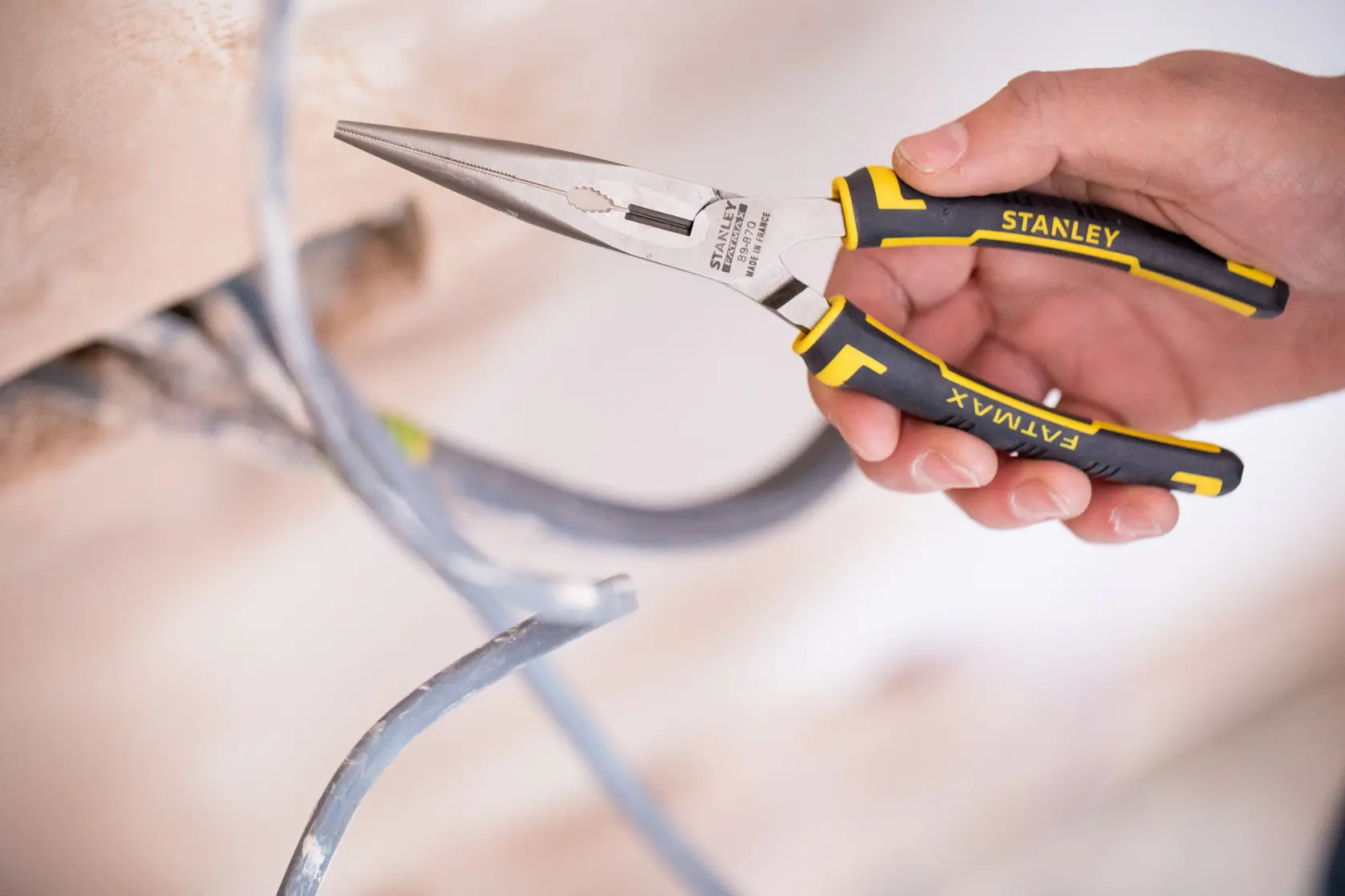 Stanley 89-870 FATMAX long nose pliers with black and yellow handle held near electrical wires.