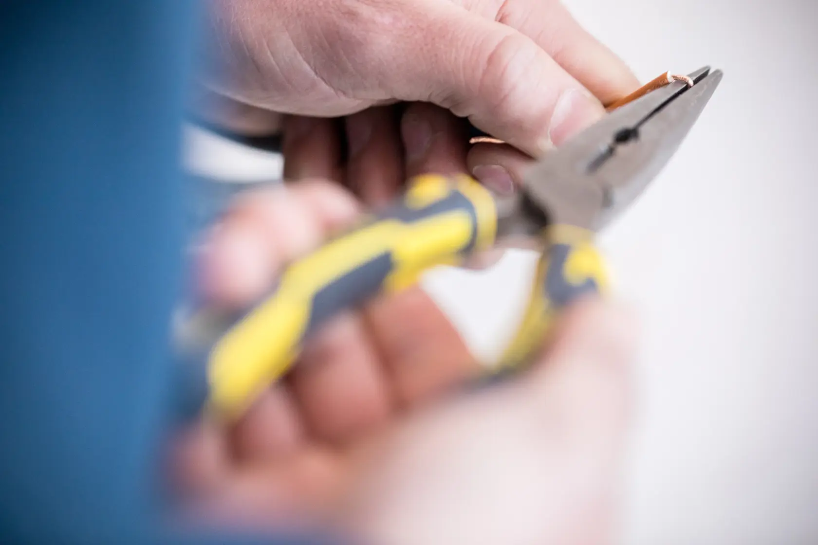 STANLEY 89-870 pliers with yellow and black handle held cutting copper wire, close-up photography.