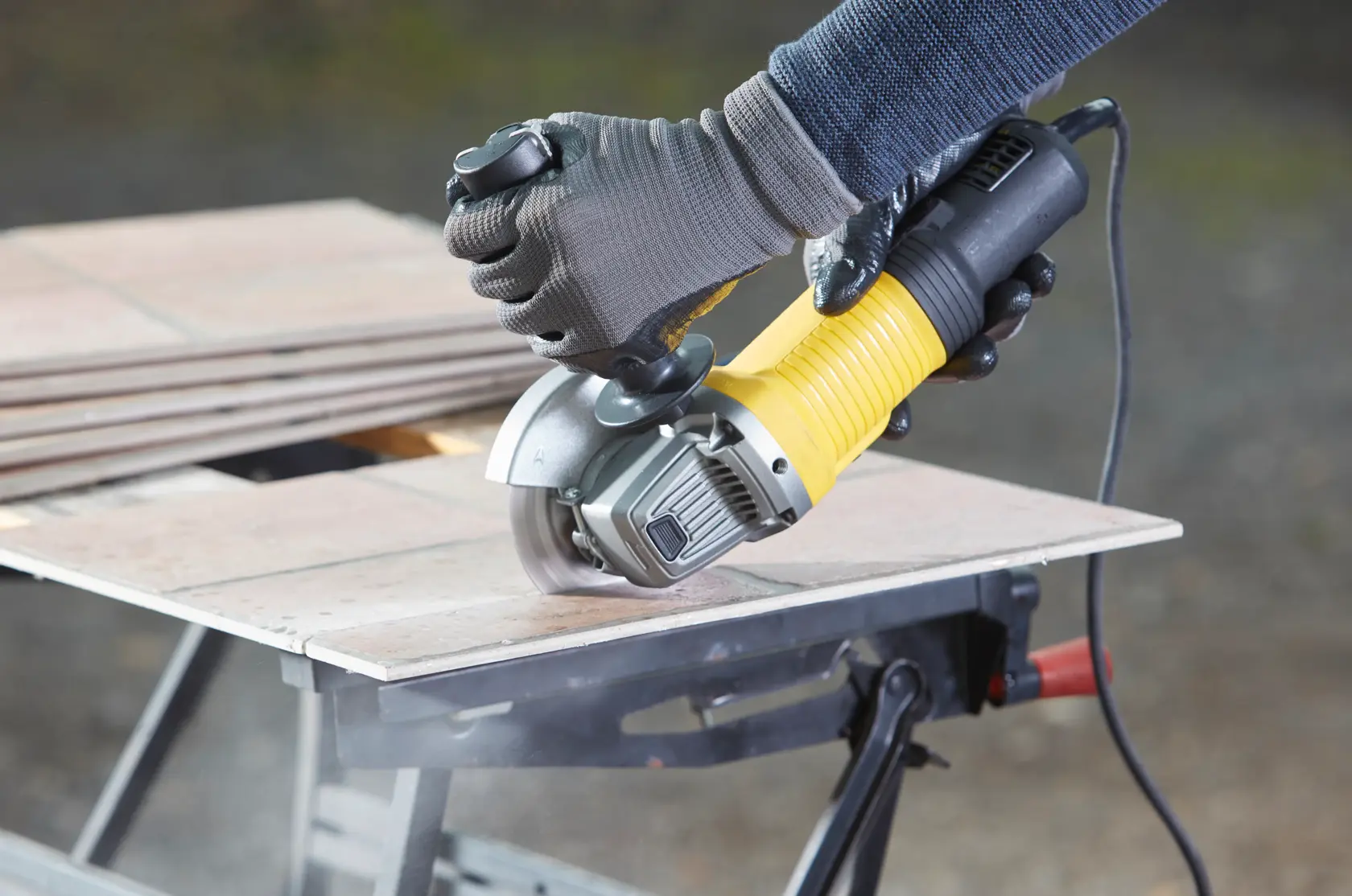 Photo of STANLEY FMEG220 angle grinder cutting tile, product in use on a workbench.