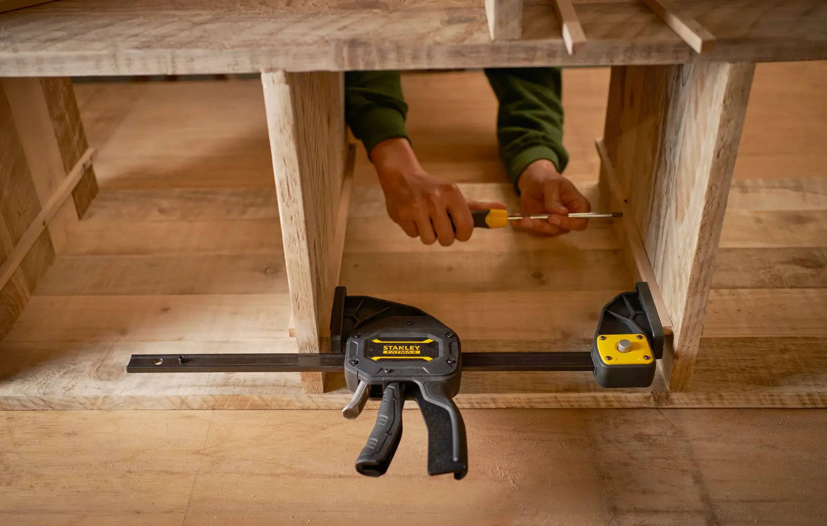 Photo of STANLEY FMHT0-83234 trigger clamp securing wooden boards during assembly, photography from front angle.