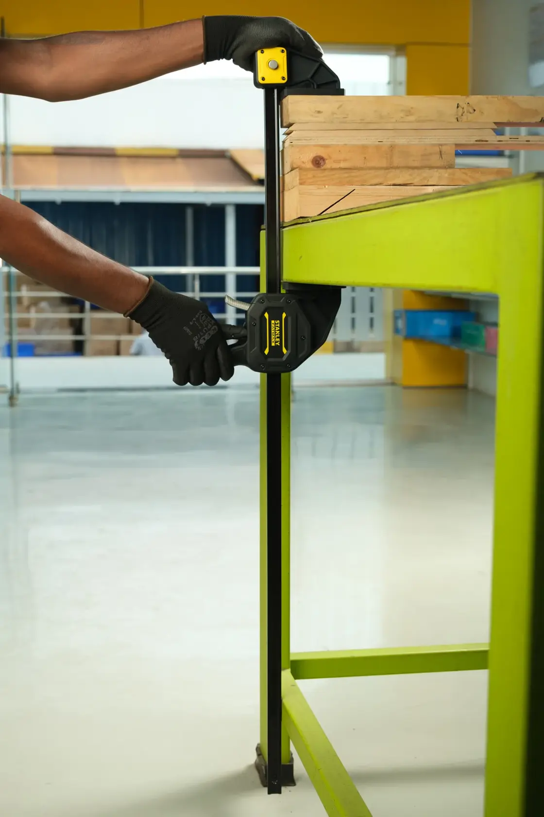 Stanley FMHT0-83241 bar clamp in use securing wood on a green workbench, close-up side angle.