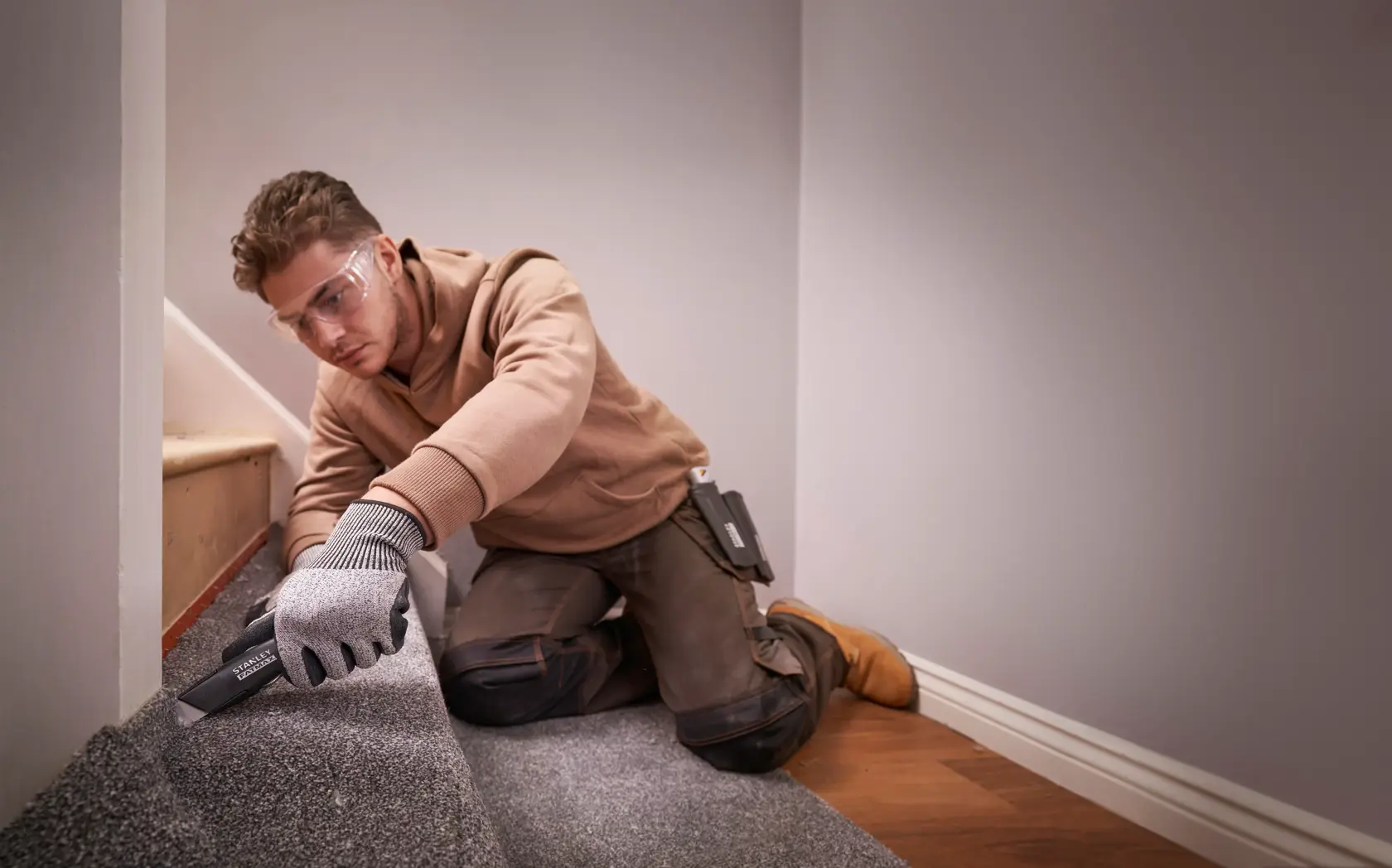 STANLEY FMHT10500-0 utility knife in use on carpet flooring, shown in home installation context.