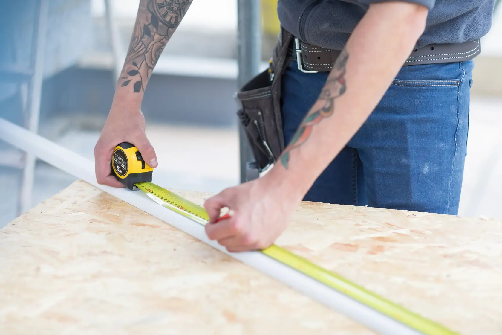 Photo of STANLEY FMHT36148-3 tape measure being used to measure a white strip on a wooden workbench.