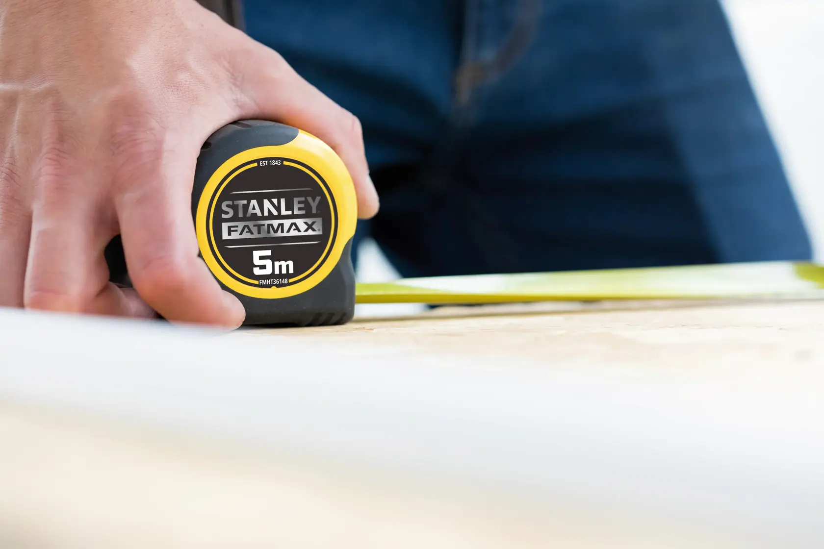 Photo of STANLEY FMHT36148-3 FATMAX 5m tape measure held by hand on wood surface.
