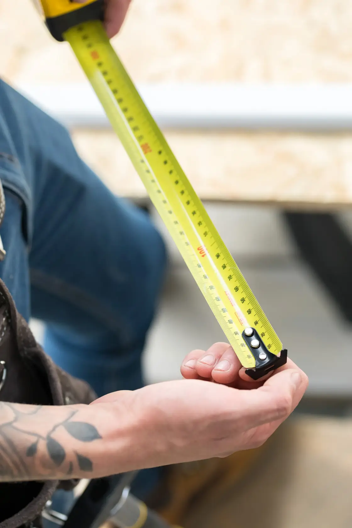 STANLEY FMHT36148-3 tape measure in use, extended by hand, yellow blade with clear markings.