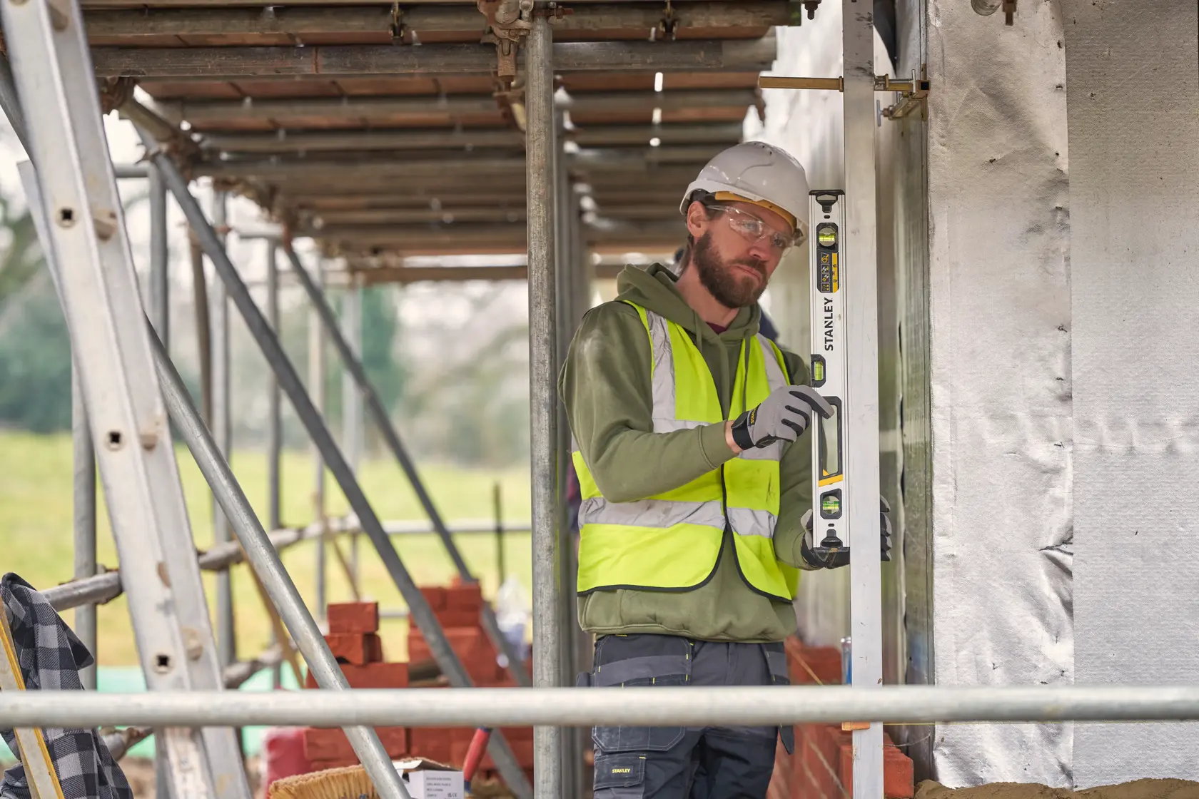 Photo of STANLEY FMHT43673-1 spirit level used by a worker in safety gear on a construction site.