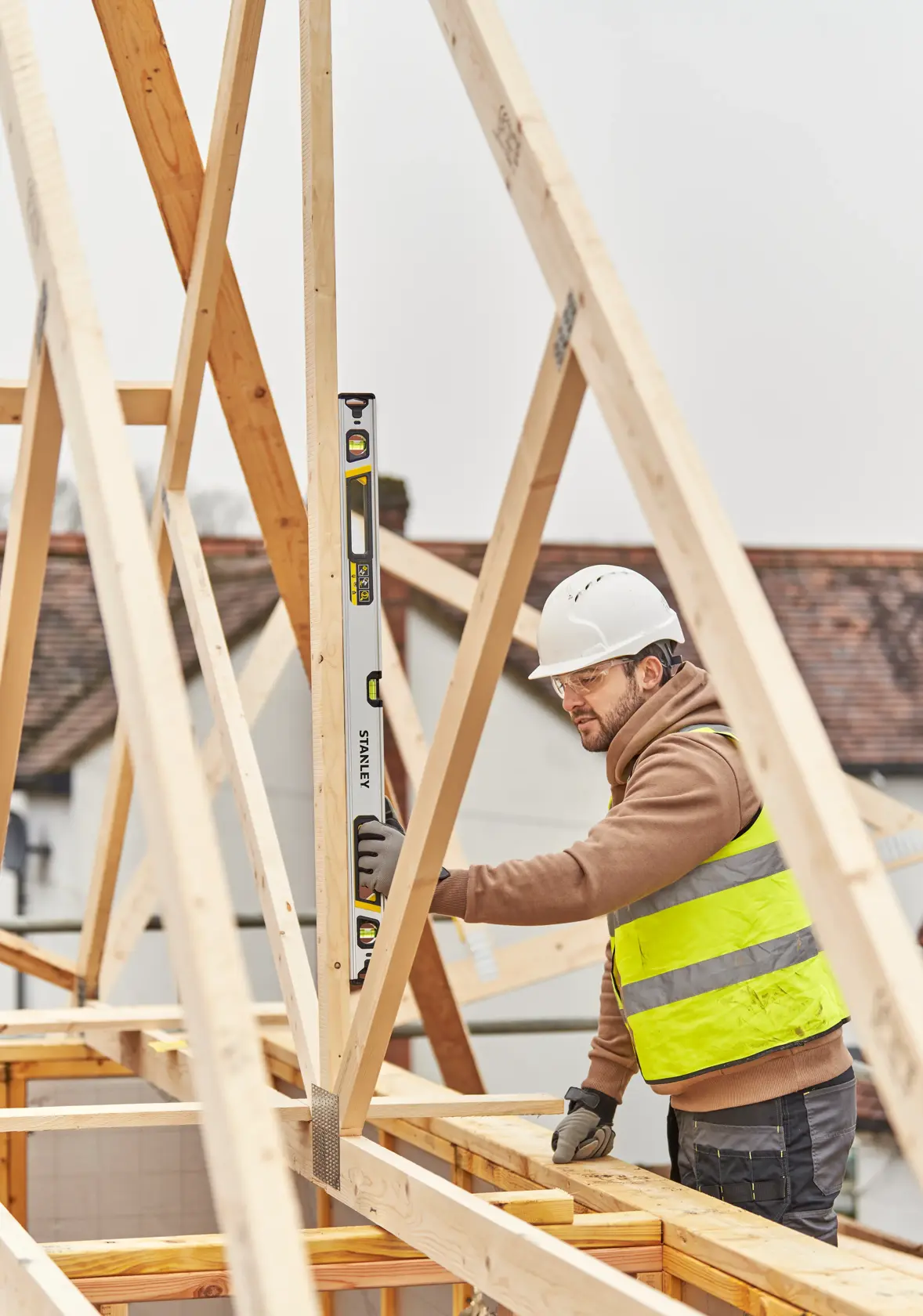 STANLEY FMHT43674-1 spirit level used by construction worker aligning a wooden beam at a building site.