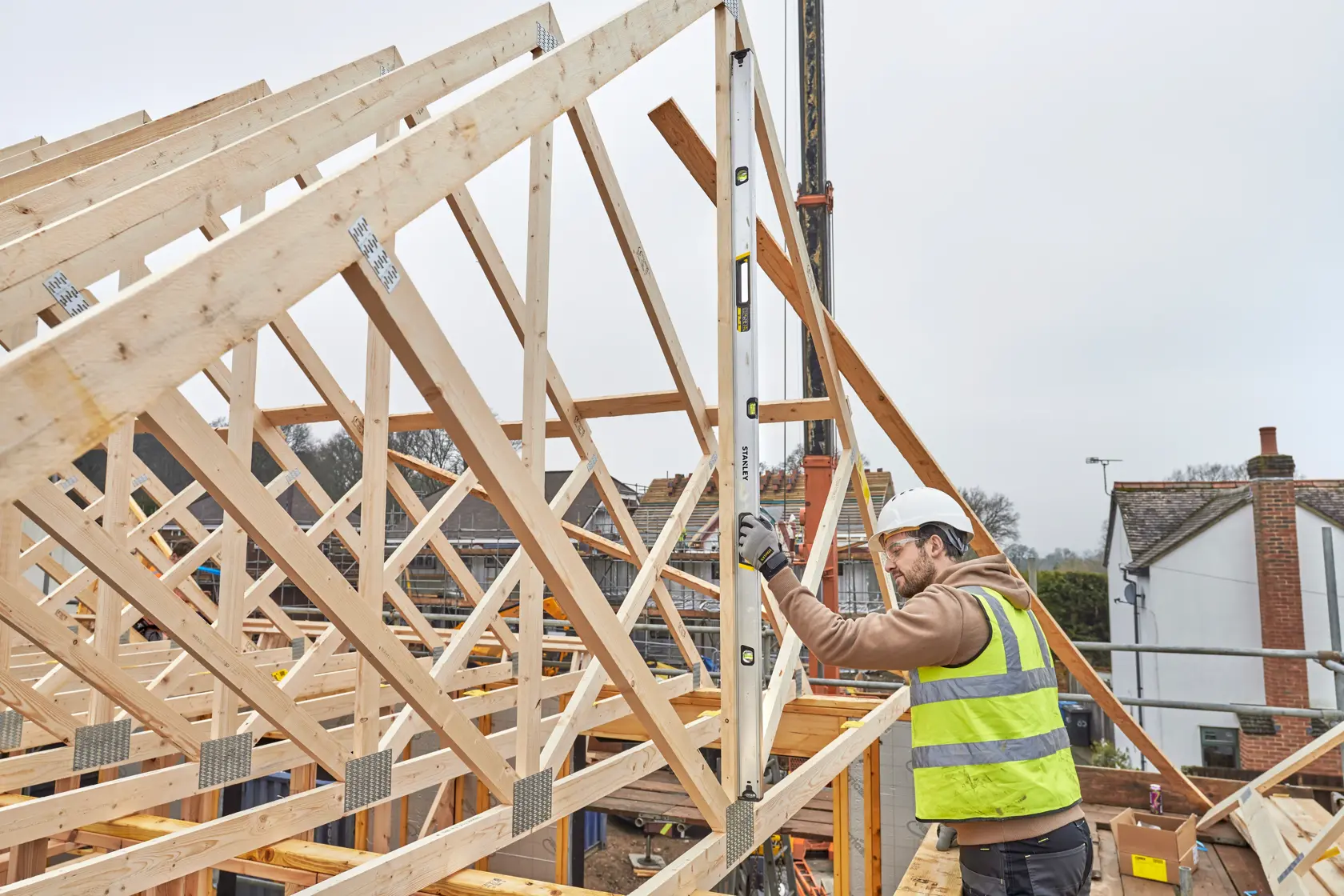 STANLEY FMHT43679-1 spirit level used by worker in high-visibility vest at construction site with timber framing.
