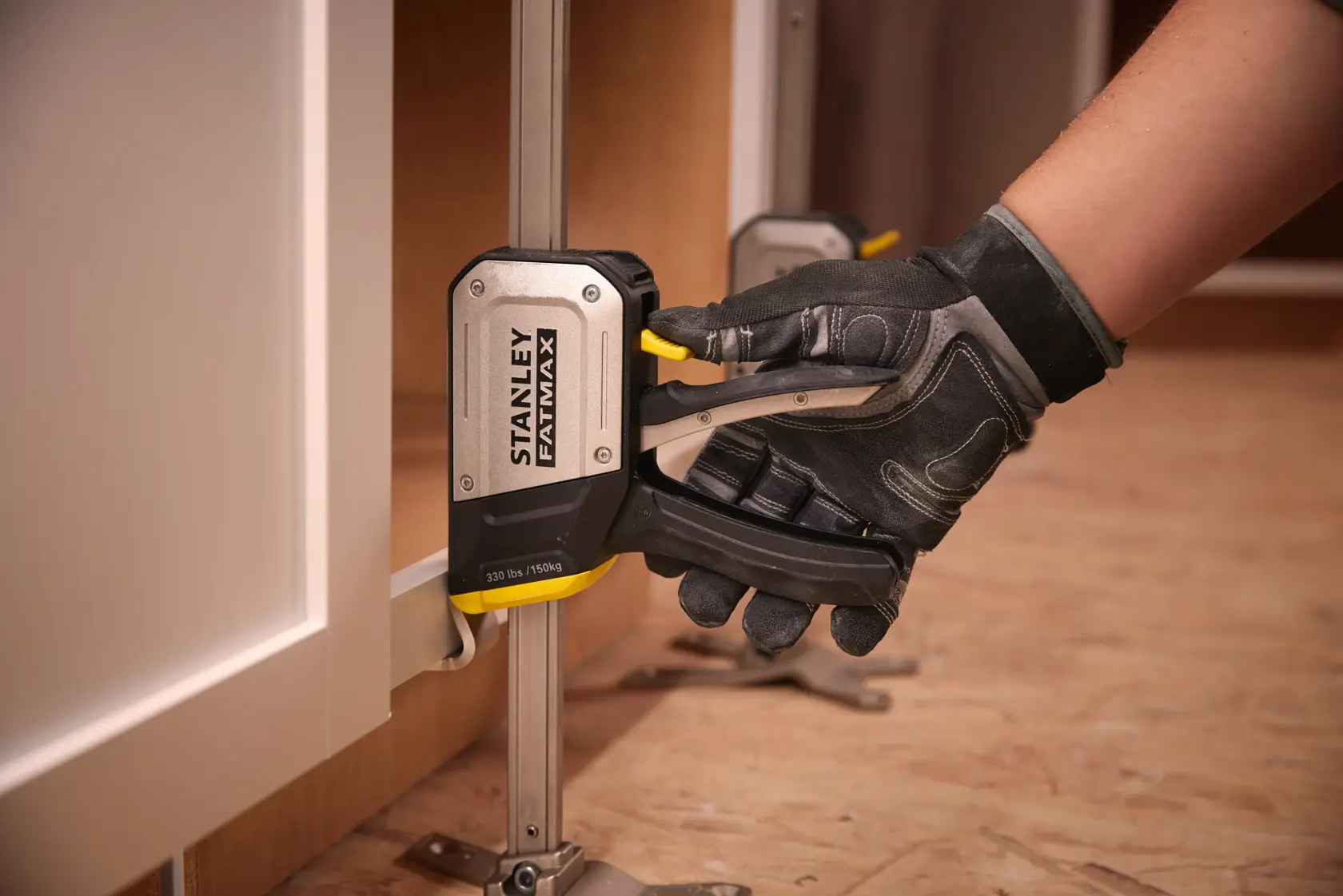 STANLEY FMHT83550-1 cabinet clamp in use, close-up angle, black and silver tool with yellow lever.