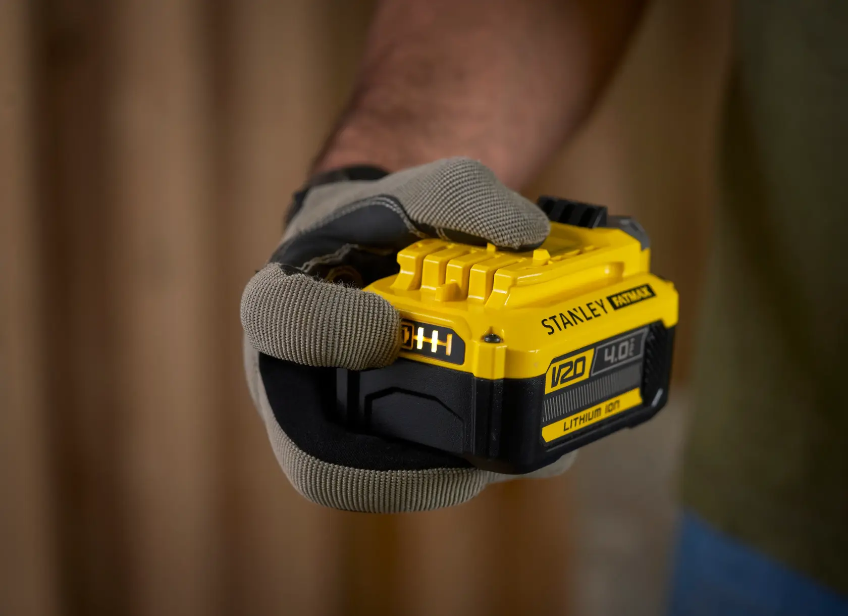 Photo of STANLEY SFMCB14M1 V20 4.0Ah lithium-ion battery held in a gloved hand.