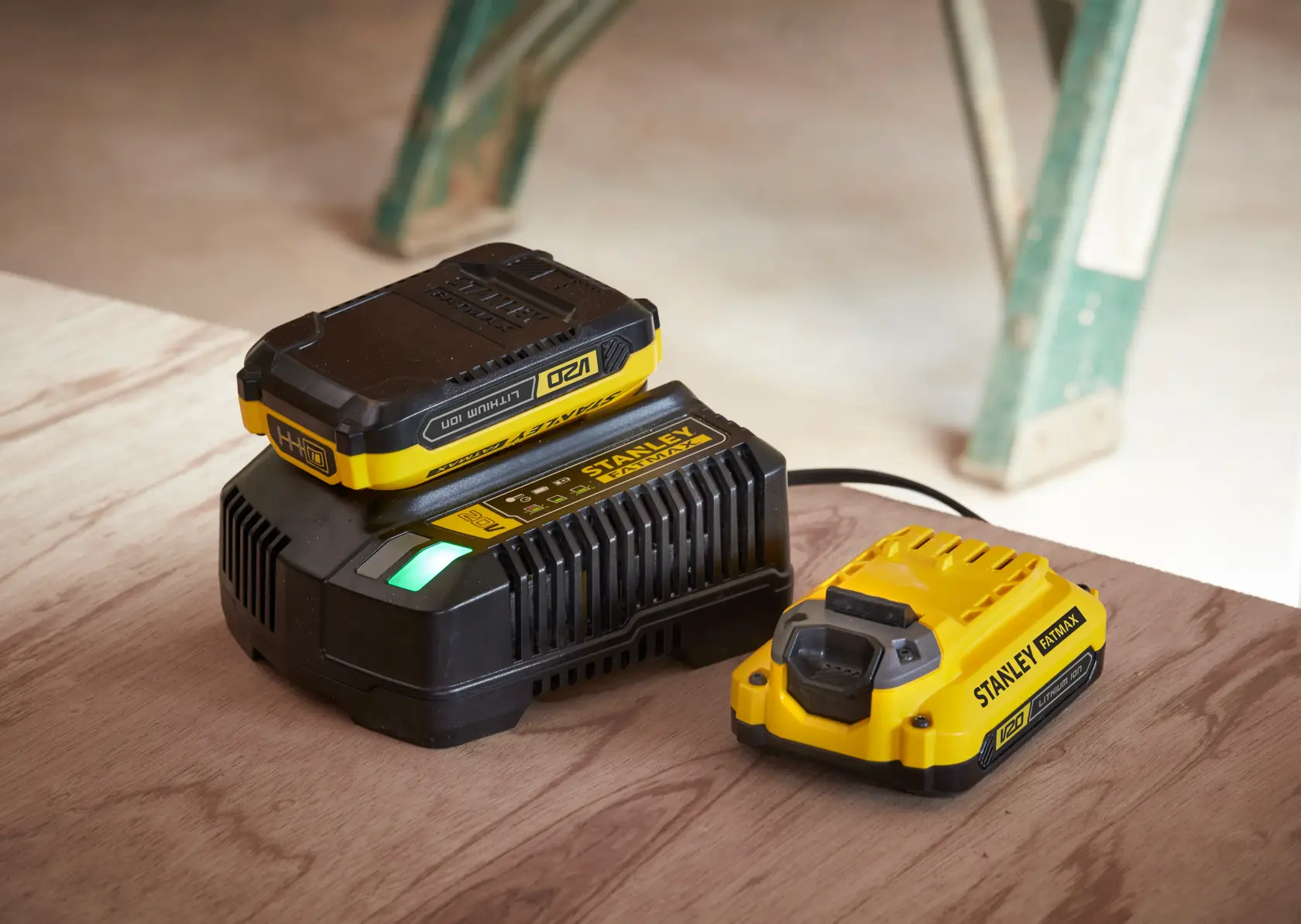 STANLEY SFMCB14 battery charger and battery, yellow and black, side angle on wooden surface.