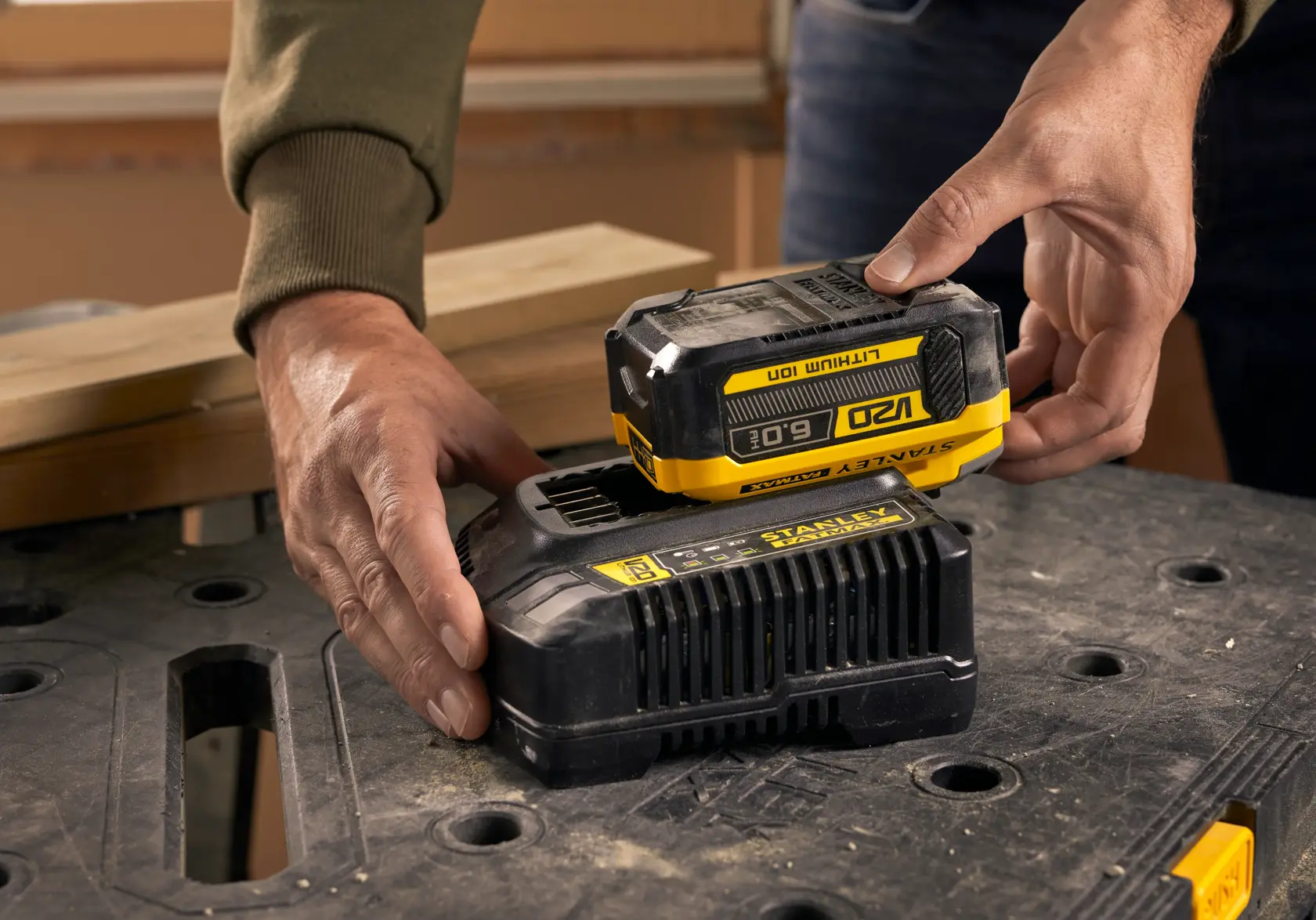 STANLEY SFMCB206 battery being placed on charger, close-up on black work surface.