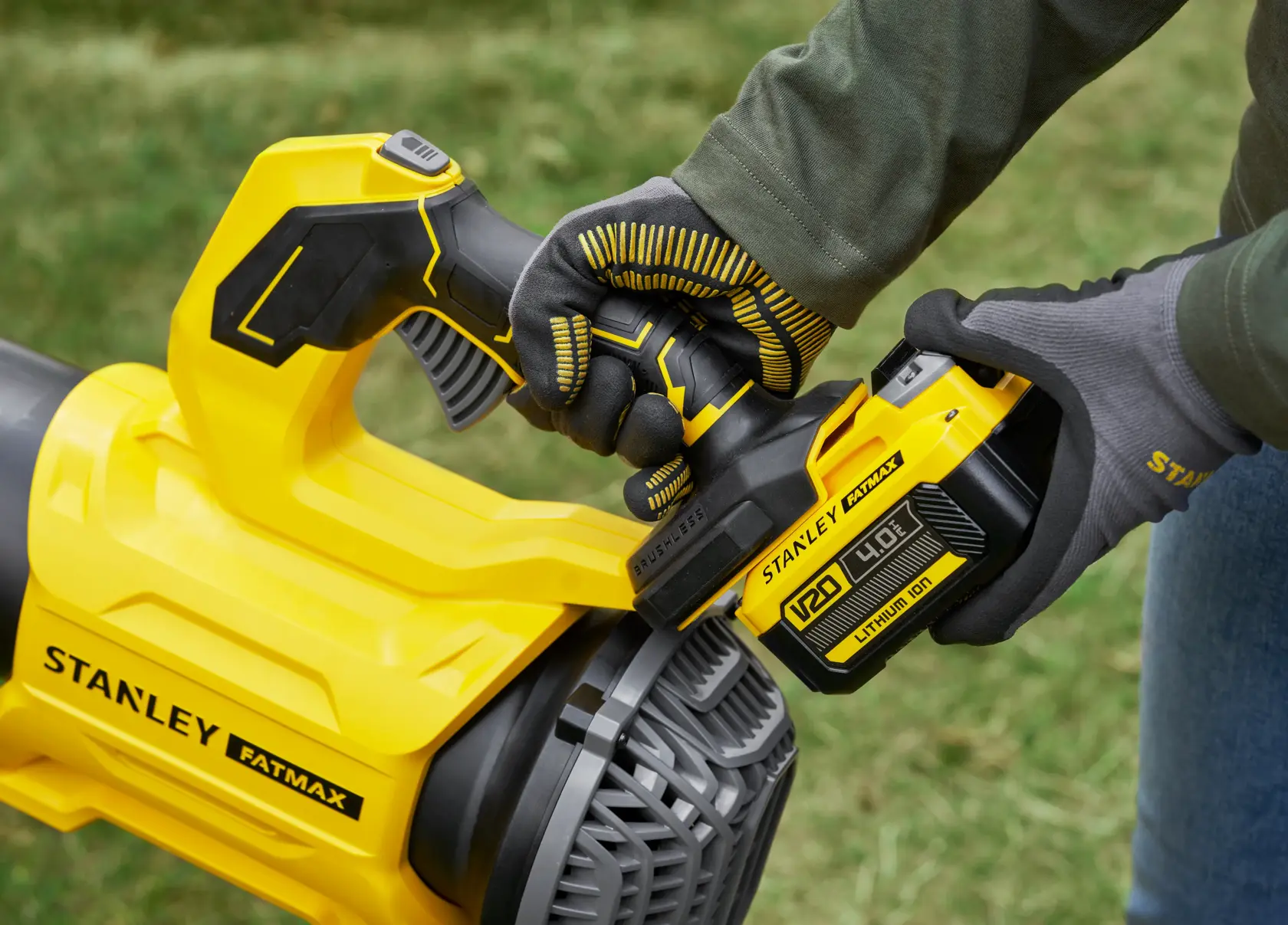 STANLEY SFMCBL730M1 cordless blower close-up with gloved hand installing battery, outdoors.