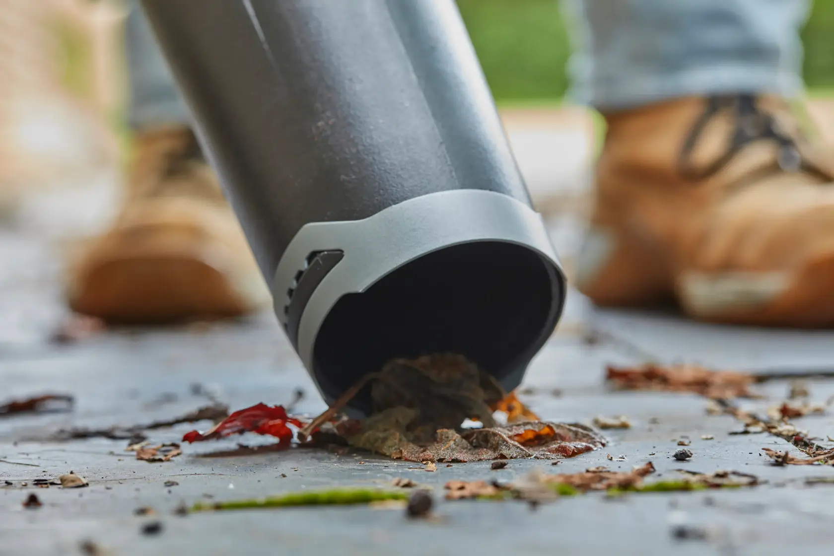 STANLEY SFMCBL7B blower tube close-up clearing leaves and debris on pavement.