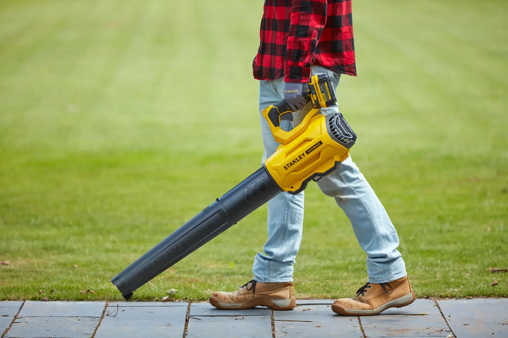 STANLEY SFMCBL7M1 cordless leaf blower shown in use on garden lawn.