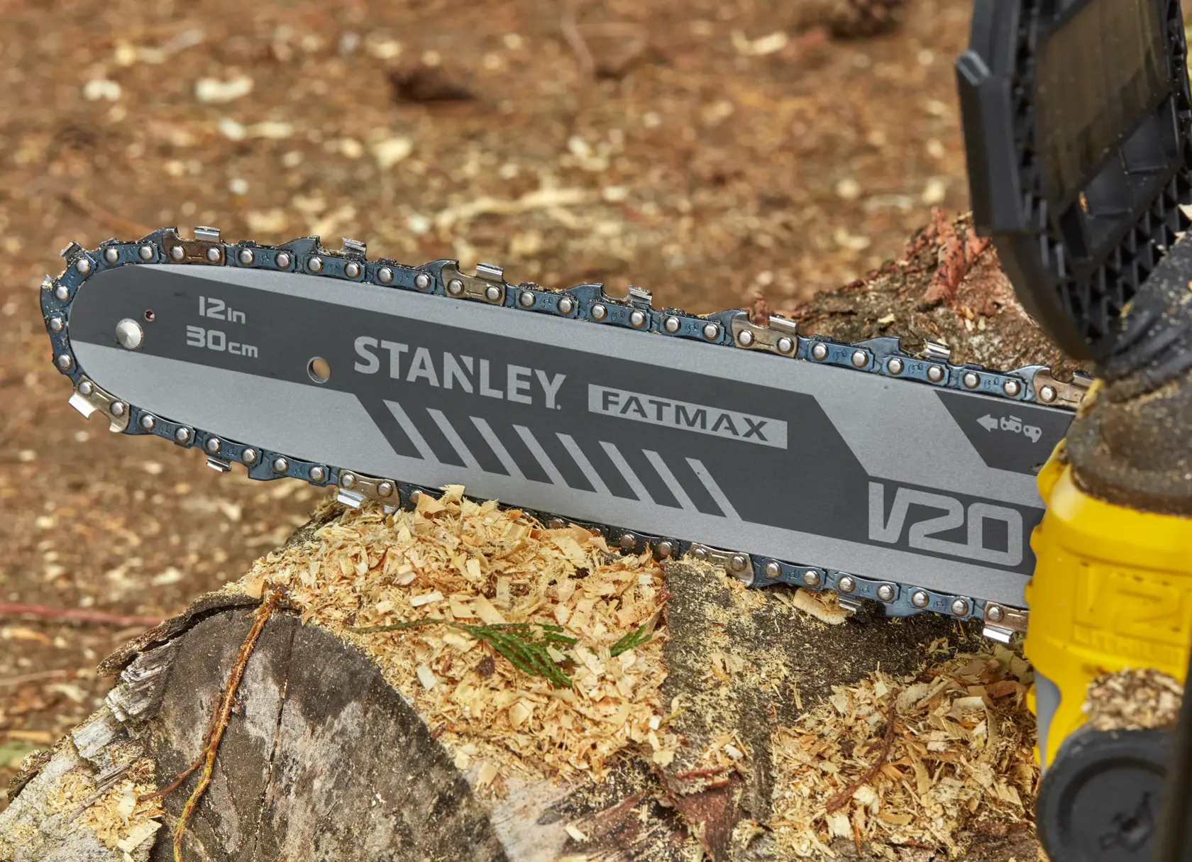 STANLEY SFMCCS630M1 chainsaw close-up, 12in bar cutting wood, FATMAX V20 branding visible.