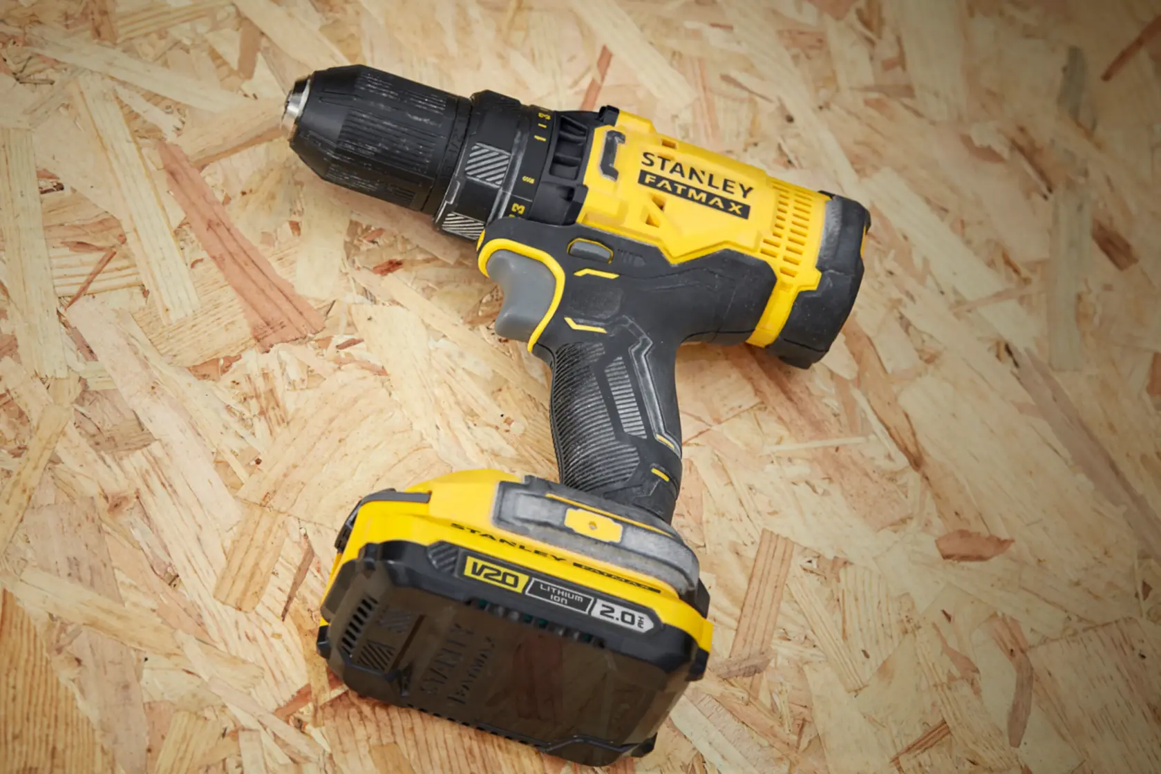 STANLEY SFMCD700D2S cordless drill driver with yellow and black design on wooden surface, side angle.