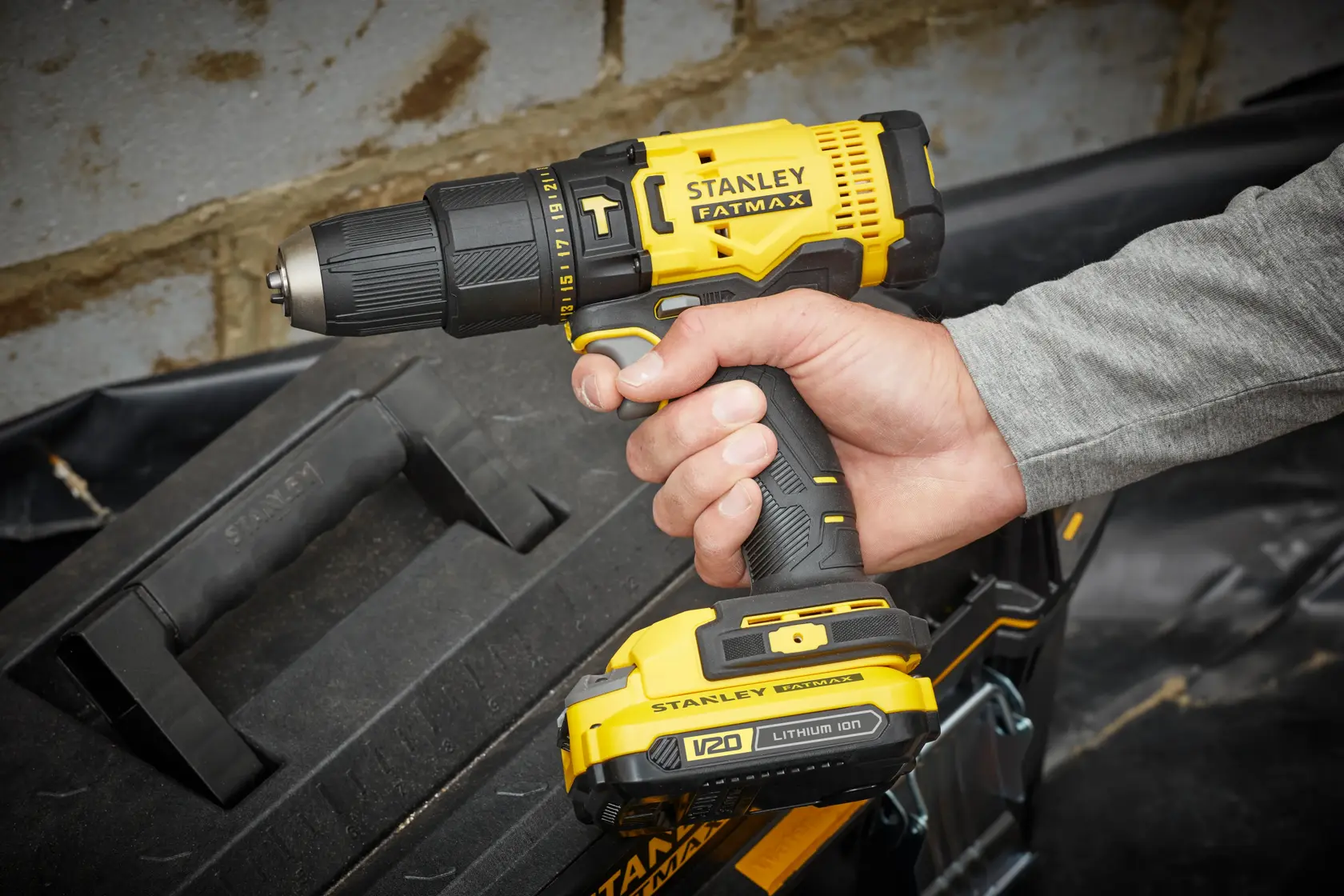 Stanley SFMCD711B cordless drill photographed in hand, yellow and black design, close-up view.