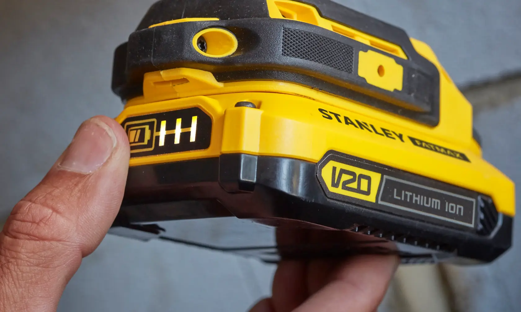 STANLEY SFMCD711DM2 V20 lithium ion battery, close-up angle, yellow and black casing, battery indicator.