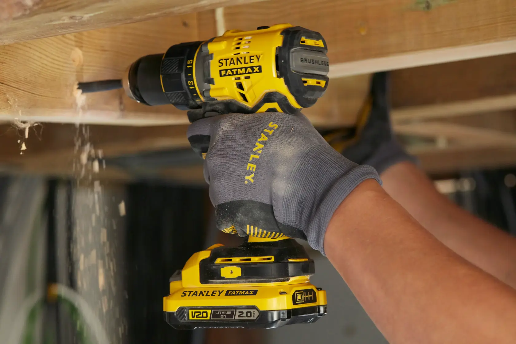 STANLEY SFMCD720B cordless brushless drill used for wood drilling, yellow and black, close-up action.
