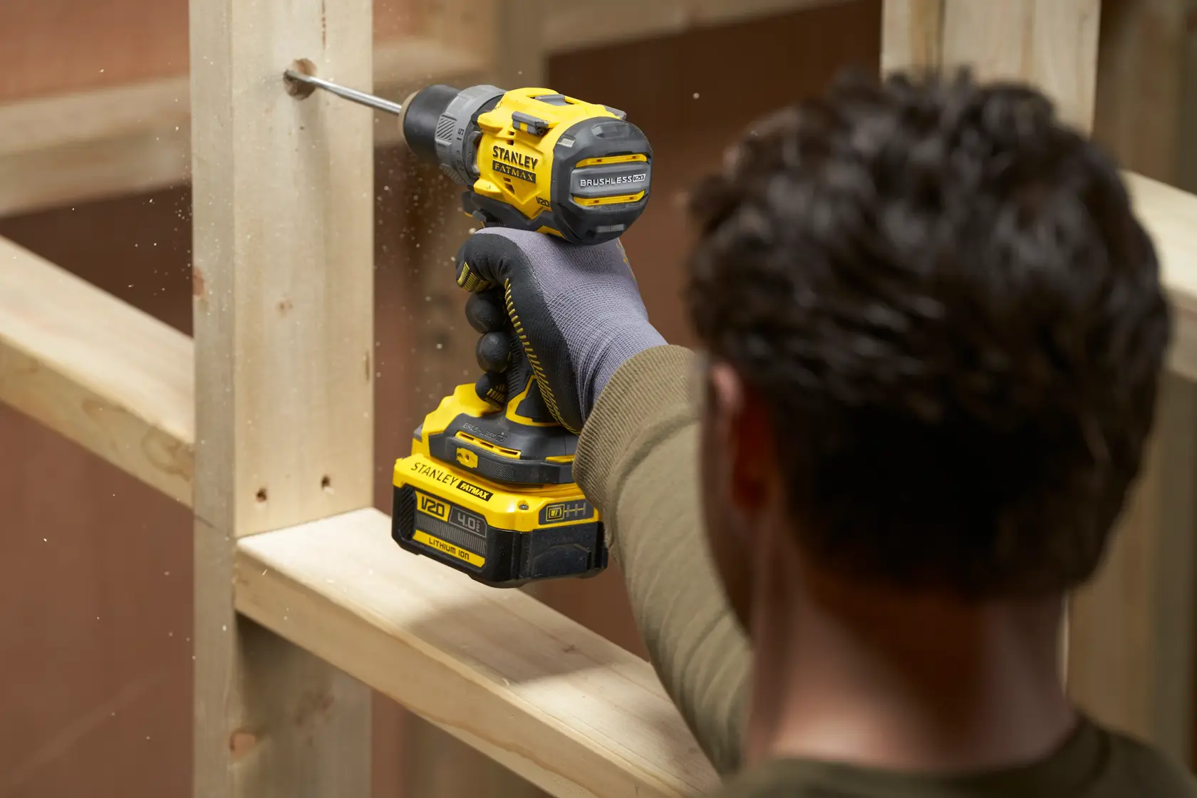 Photo of STANLEY SFMCD725B cordless drill in use drilling into wood, side angle, black and yellow design.