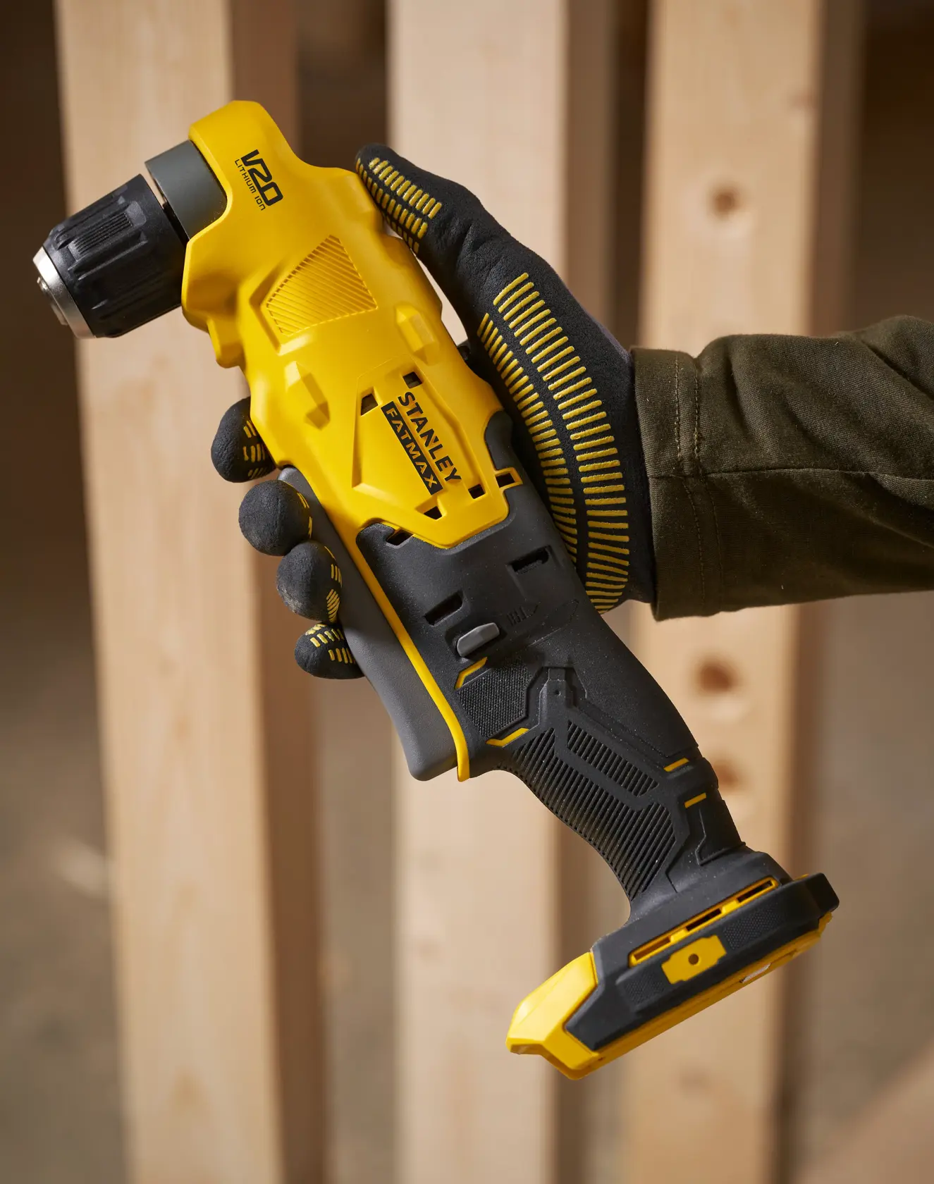 Stanley SFMCD750B cordless right angle drill in yellow and black, held in gloved hand, construction setting.
