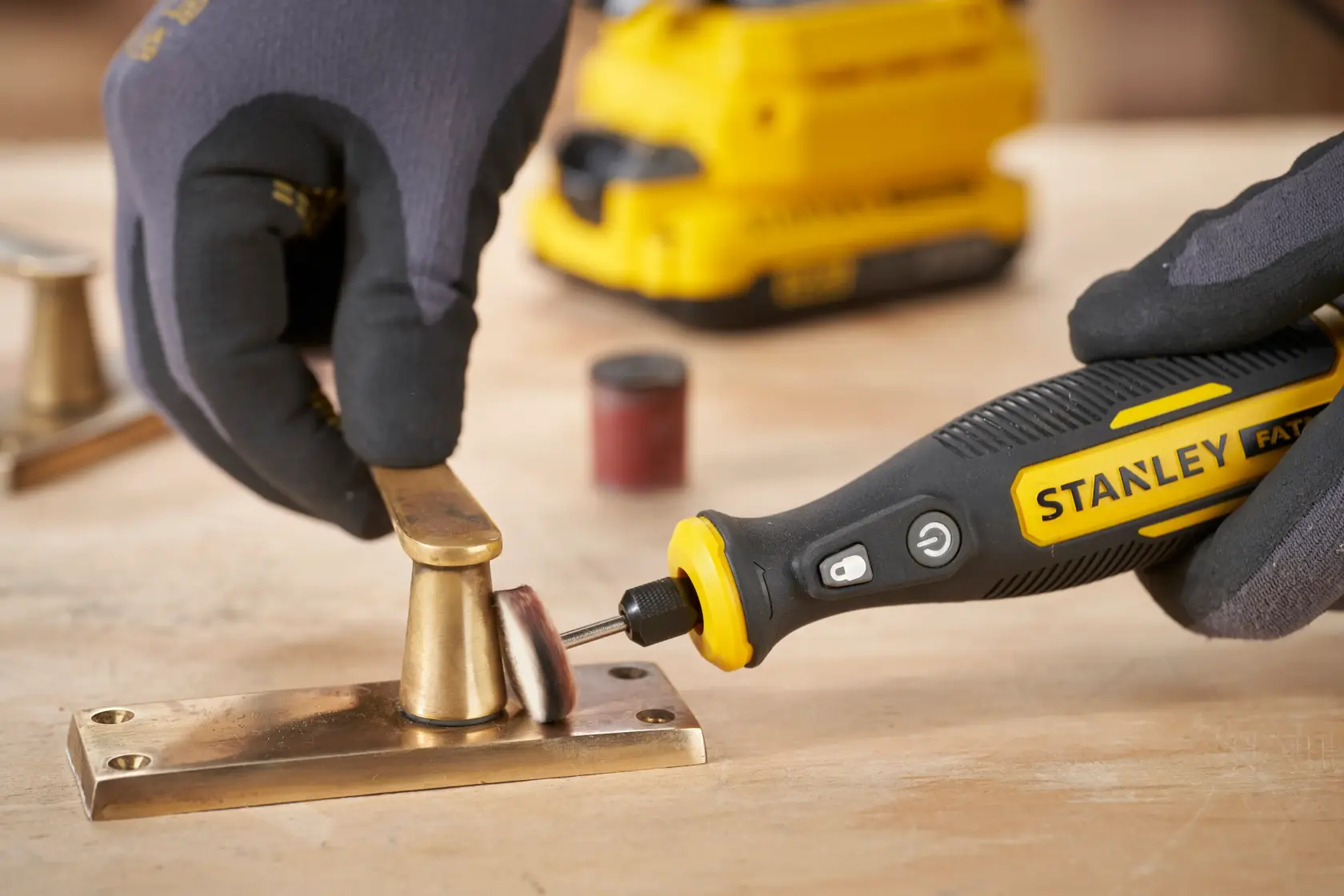 STANLEY SFMCE030B rotary tool polishing brass hardware on a wooden surface, close-up photography.