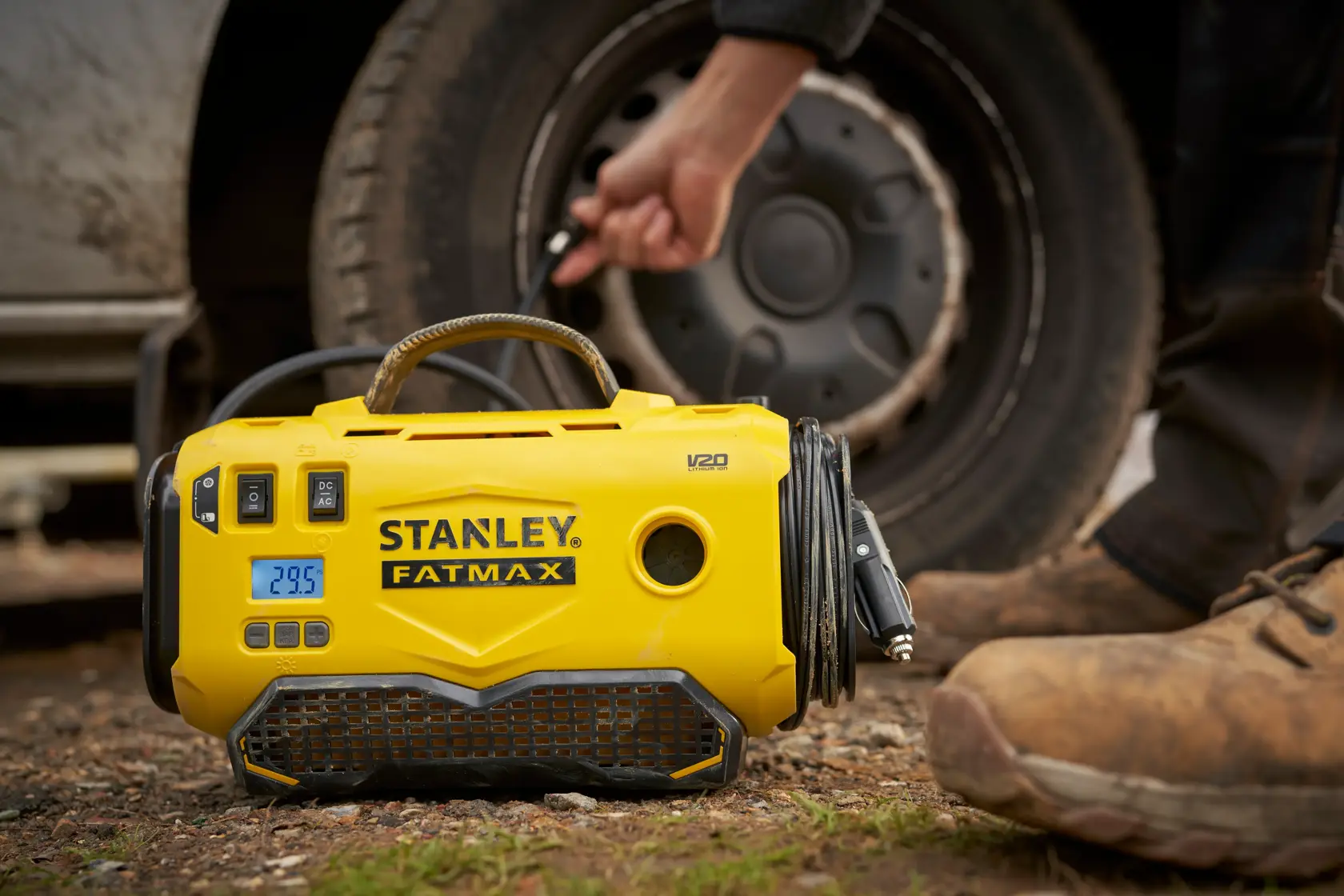 STANLEY SFMCE520B portable yellow tire inflator in use beside vehicle wheel outdoors.