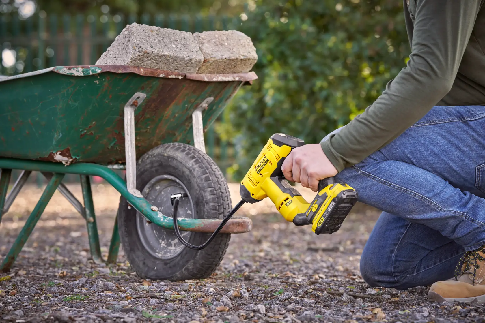 Photo of STANLEY SFMCE521B inflator being used to inflate a wheelbarrow tire outdoors.