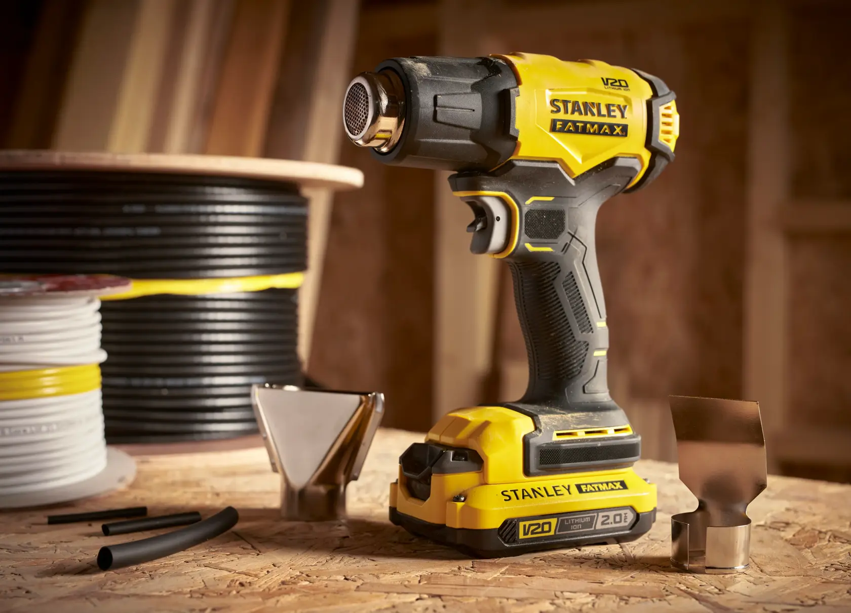 STANLEY SFMCE530B heat gun with accessories, yellow and black, photography of product on workshop table.