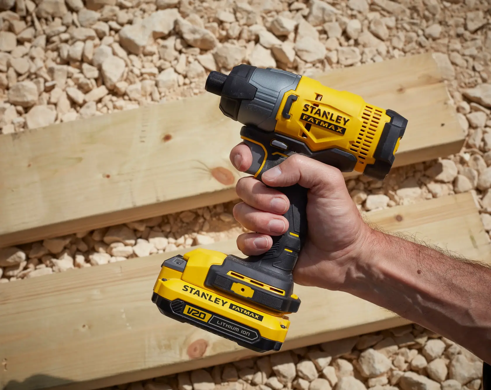 Stanley SFMCF800DM2 cordless impact driver held over wooden boards, yellow and black design.