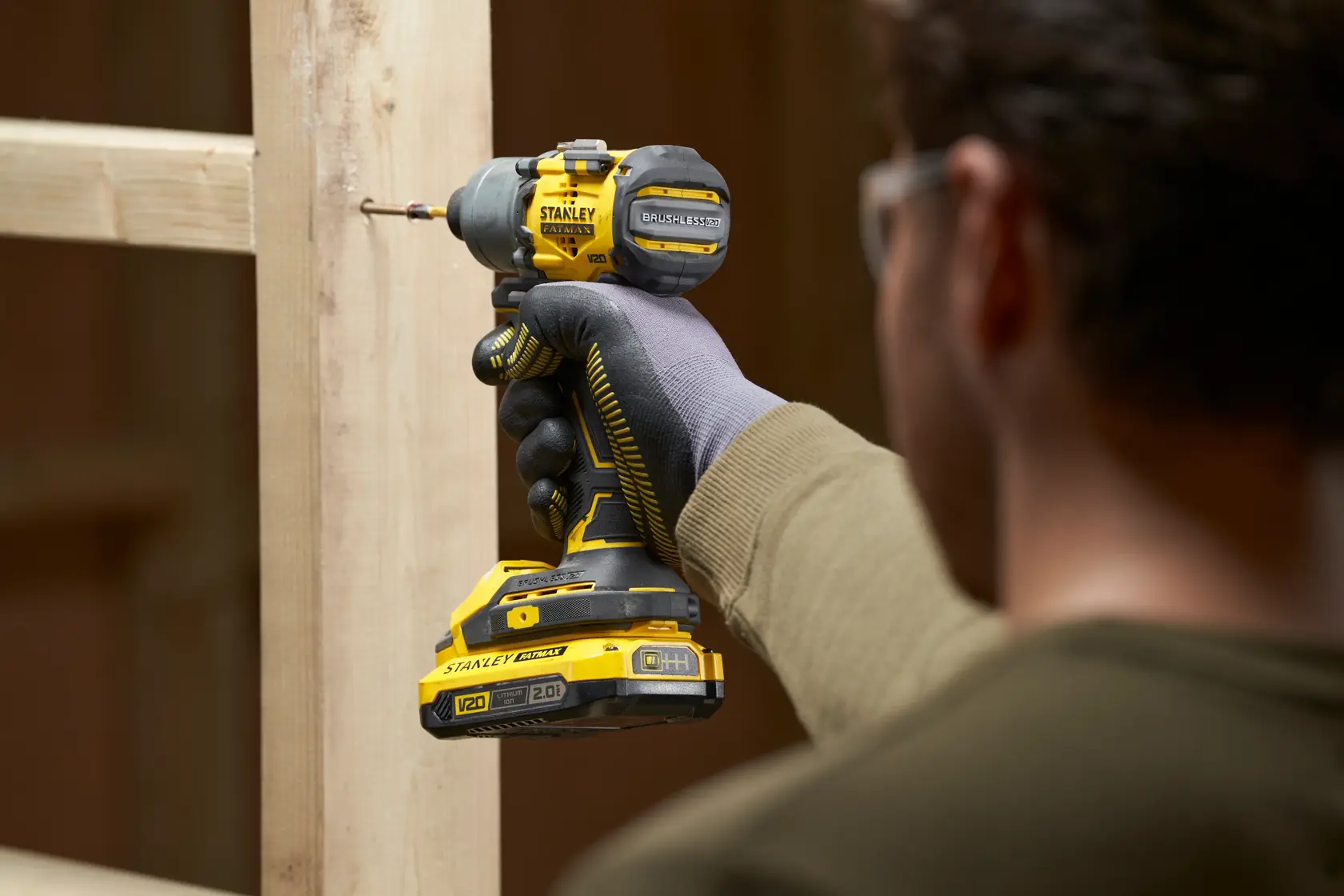 Photo of STANLEY SFMCF830B cordless impact driver being used on wooden frame, close-up side view.