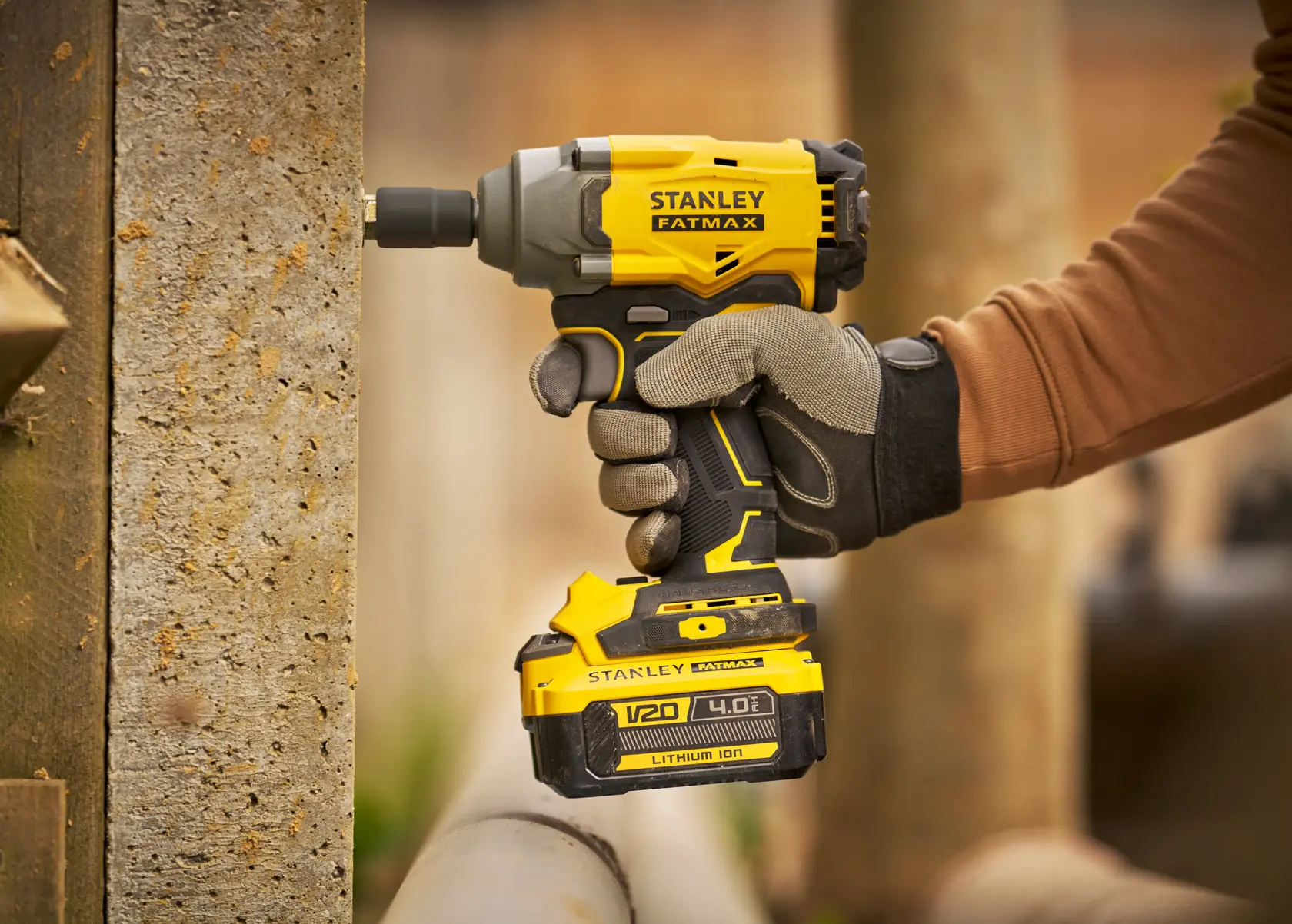 Stanley SFMCF920B cordless impact driver in use, yellow and black design, worker holding tool.