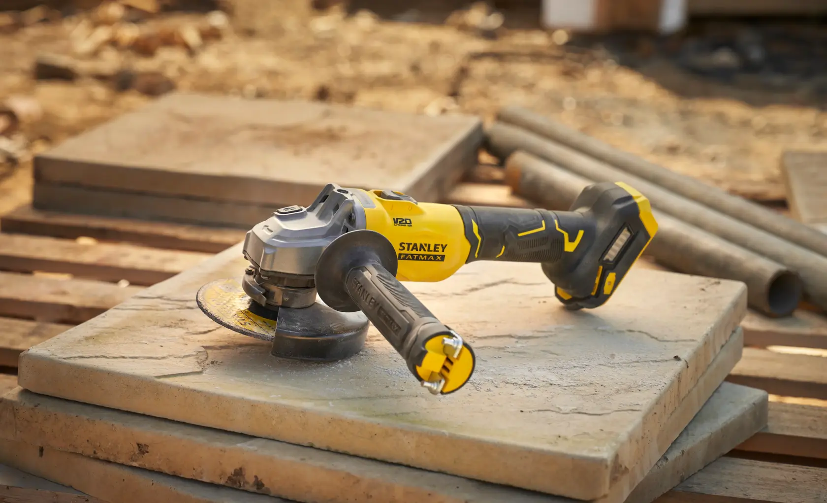 STANLEY SFMCG710B-XJ cordless angle grinder on stone slab, yellow and black, photo outdoors.